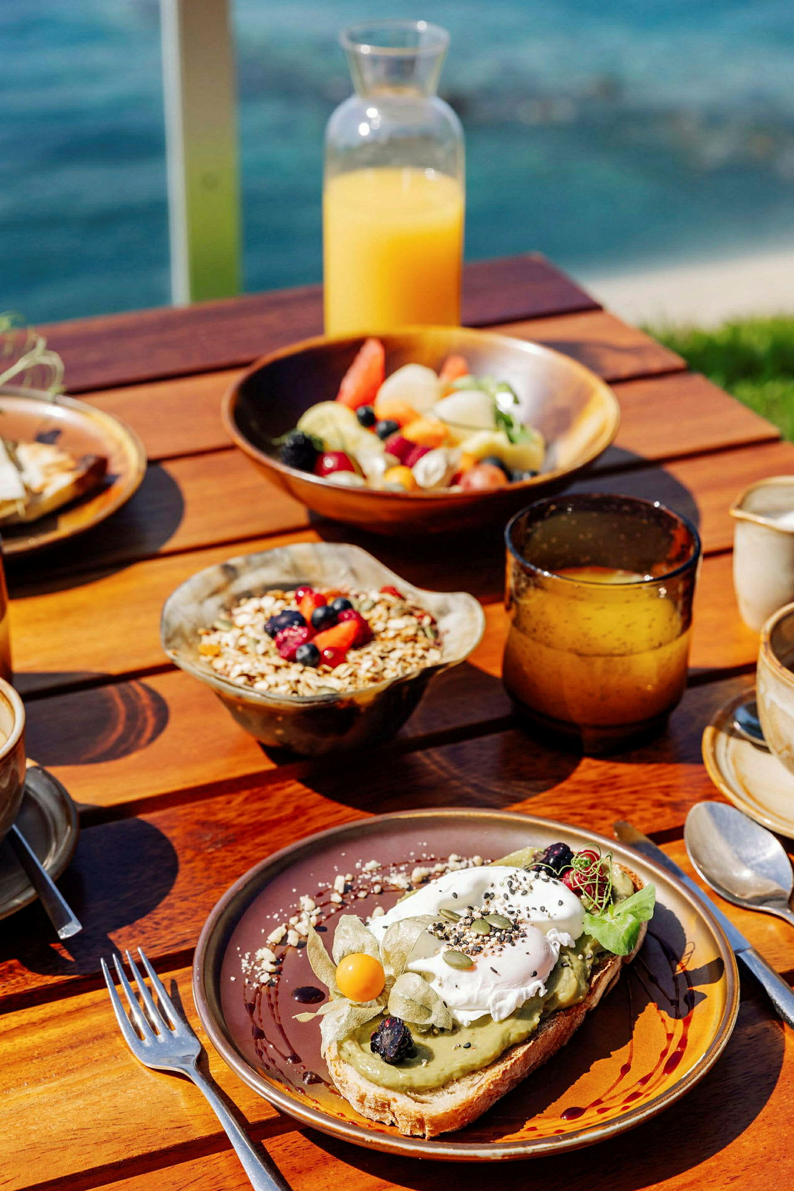 En frukostservering med juice, frukt, granola och avokadomacka. (AI-genererad text)