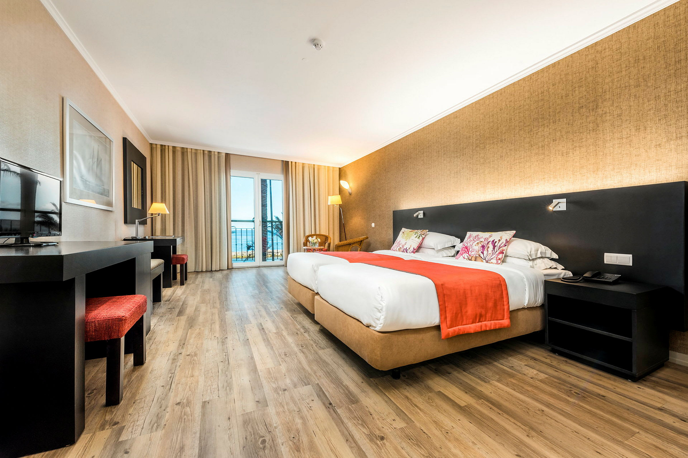 Ett hotellrum med två sängar, ett skrivbord och ett fönster mot balkongen. (AI-genererad text)