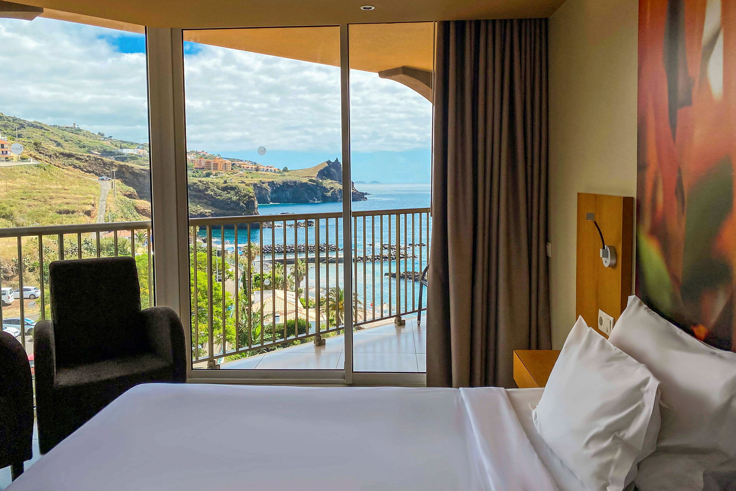 Vy från hotellrum med utsikt över hav och kuperad terräng. (AI-genererad text)
