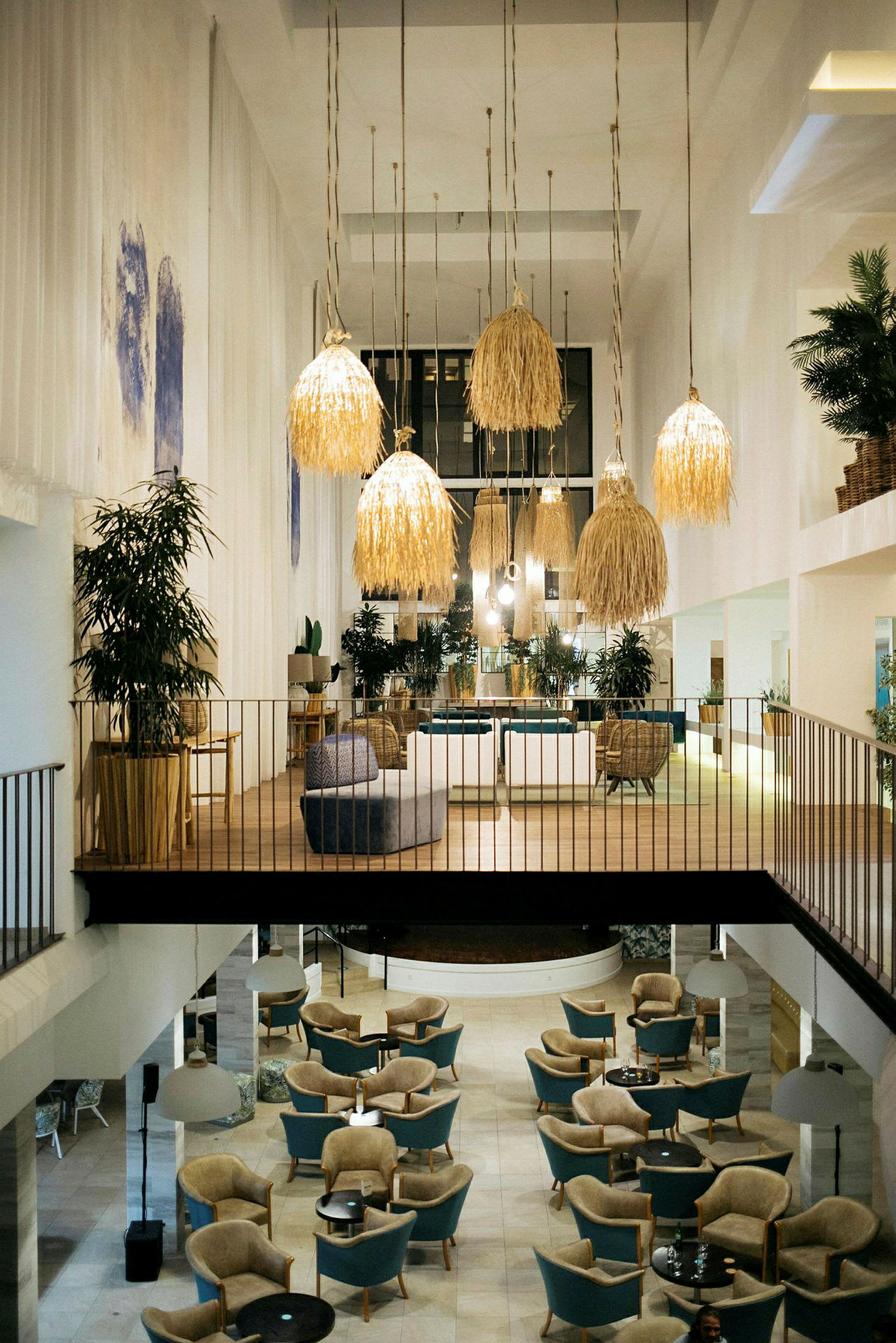Interiören av ett rymligt och elegant hotellområde med sittgrupper och stora hängande lampor. (AI-genererad text)