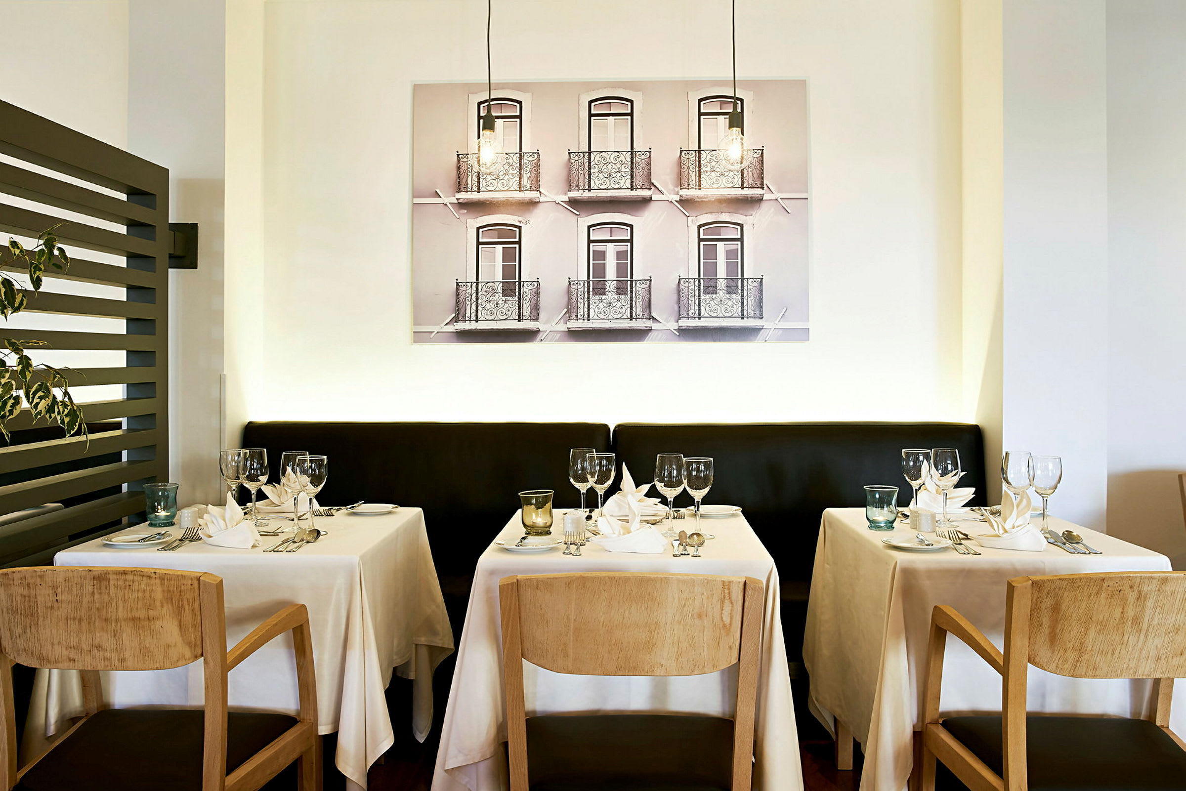 Restaurang med dukade bord framför en vägg med fotokonst. (AI-genererad text)
