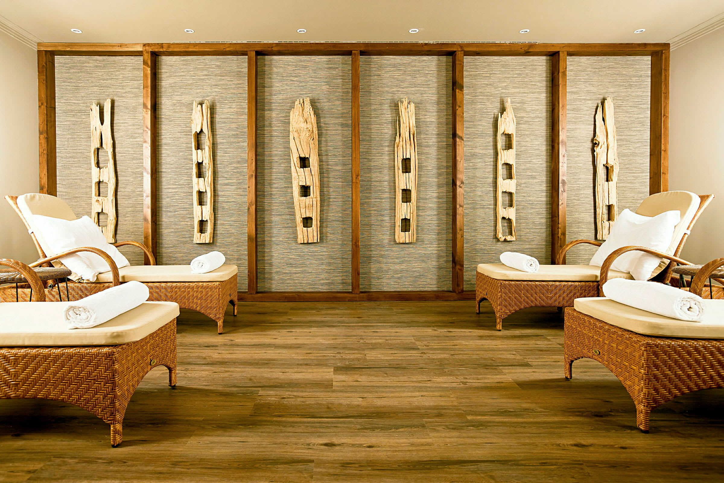 En spa-lounge med rottingmöbler och dekorativa trädetaljer på väggen. (AI-genererad text)