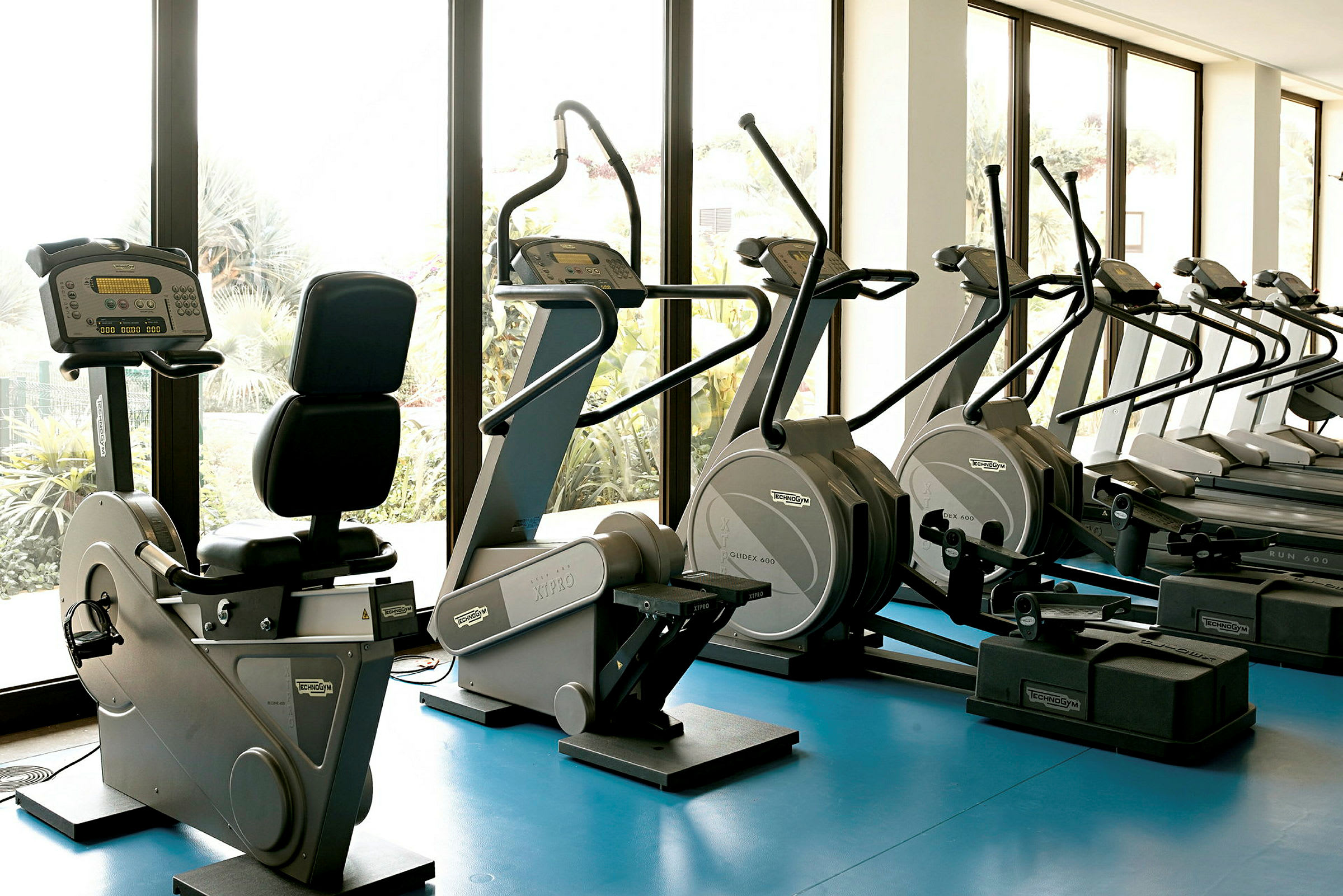 Interiör av ett gym med träningsmaskiner nära stora fönster. (AI-genererad text)