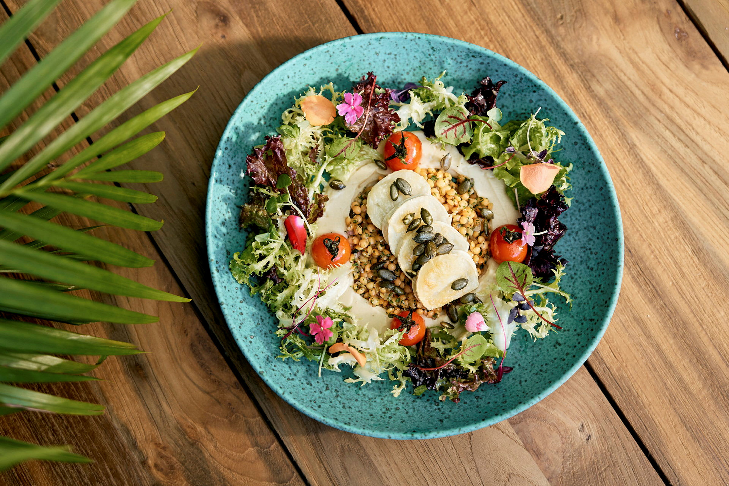 En tallrik med sallad, grönsaker och hummus på ett bord. (AI-genererad text)