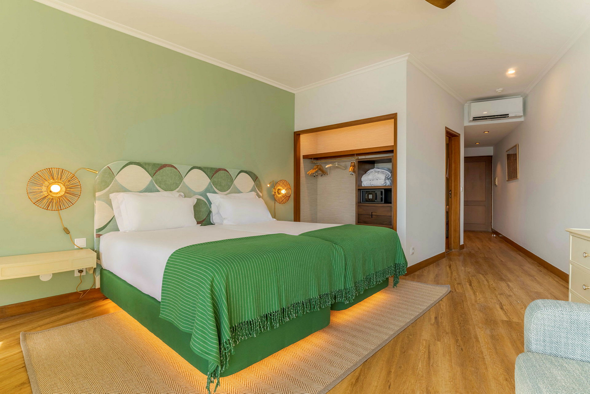 Ett hotellrum med två enkelsängar, grön inredning och en modern garderob. (AI-genererad text)