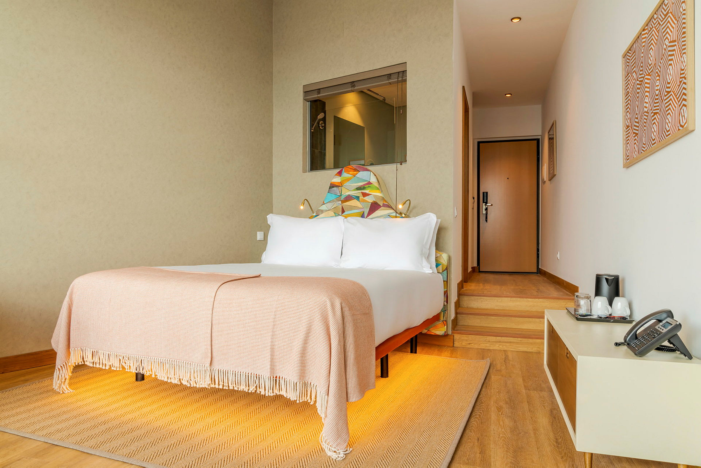 Ett hotellrum med en bäddad säng, dekorativa element på väggen och ett litet sidobord. (AI-genererad text)