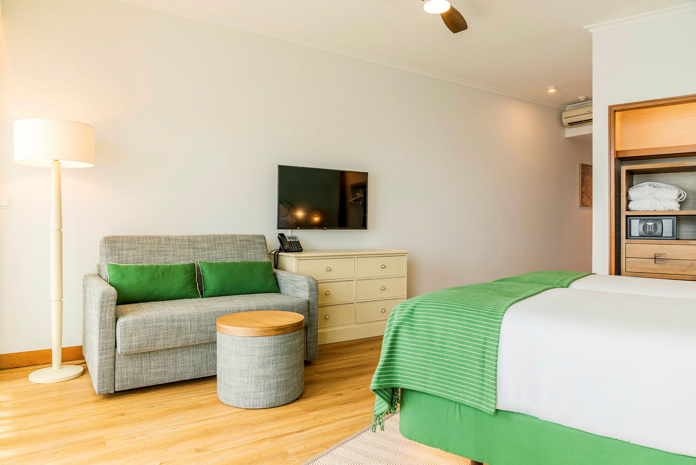 Ett hotellrum med en soffa, ett litet bord, en säng och en TV på väggen. (AI-genererad text)