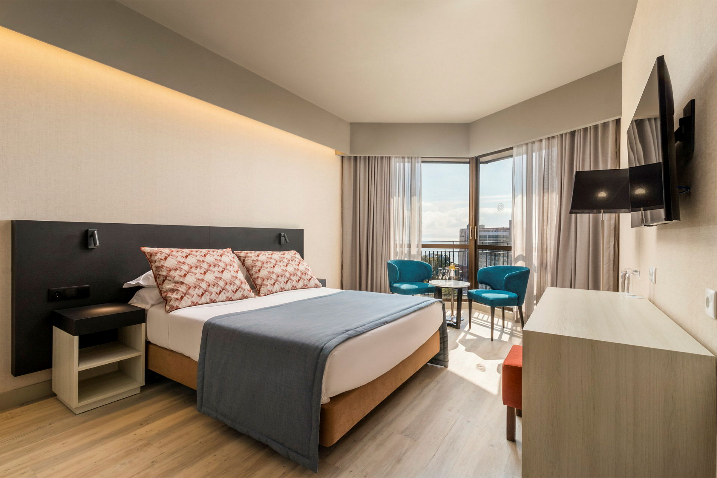 Modernt hotellrum med en dubbelsäng, sittgrupp och utsikt. (AI-genererad text)