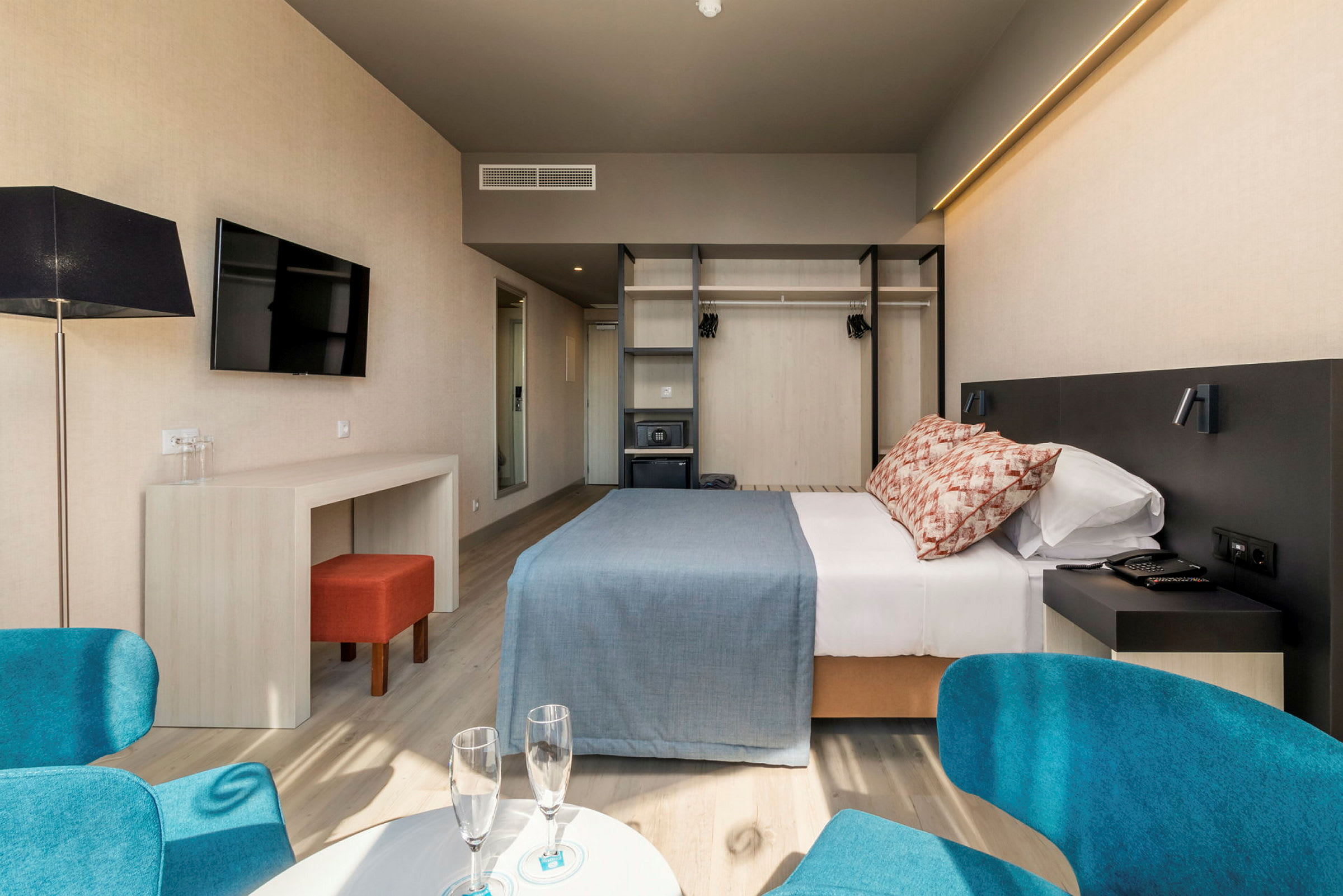Ett hotellrum med dubbelsäng, arbetsbord, stol och garderob. (AI-genererad text)