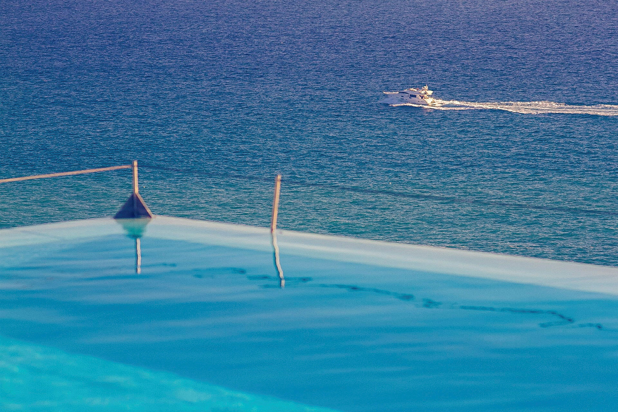 Infinitypool med utsikt över havet och en motorbåt som passerar i bakgrunden. (AI-genererad text)