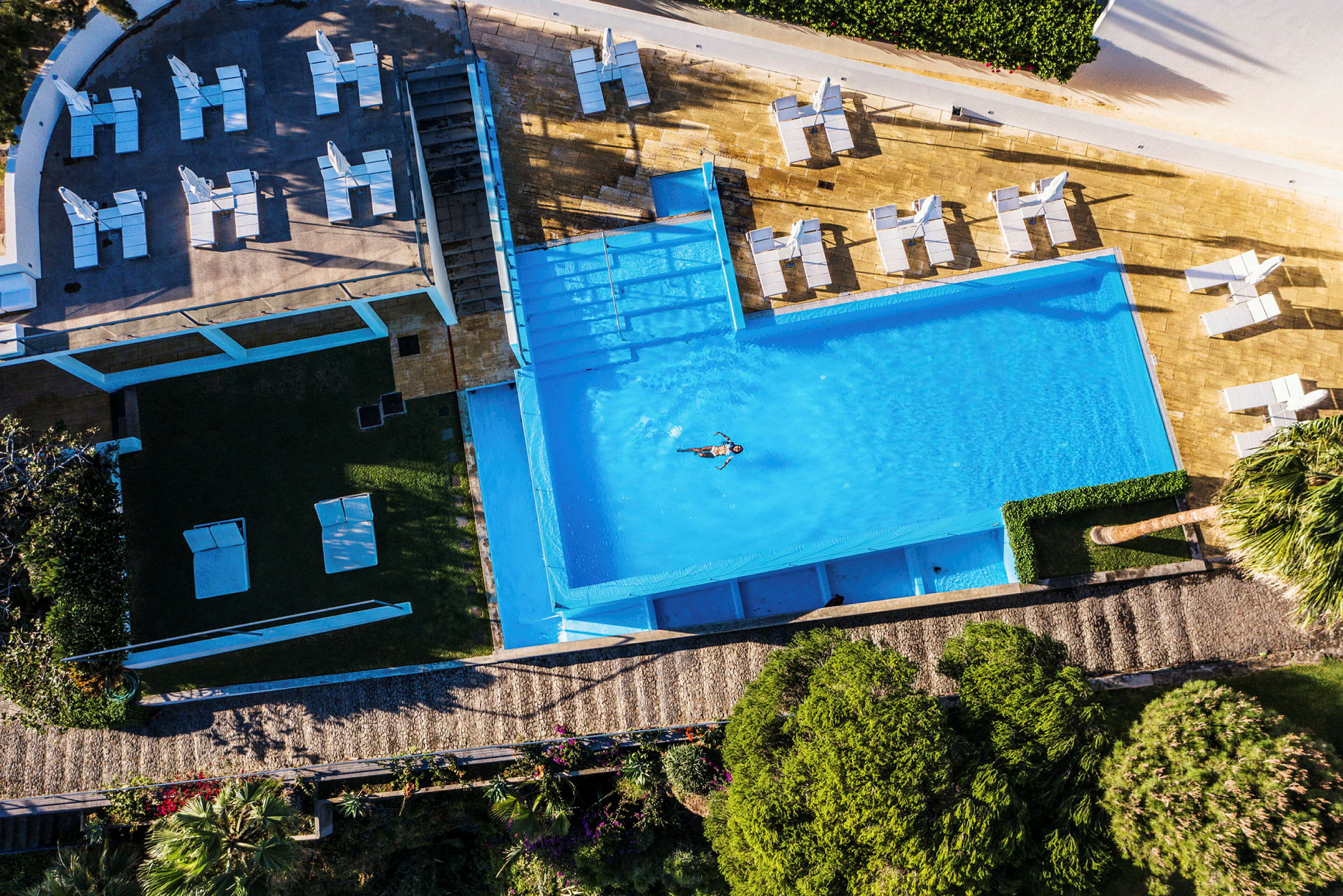 En flygbild som visar en pool och solstolar omkring. (AI-genererad text)
