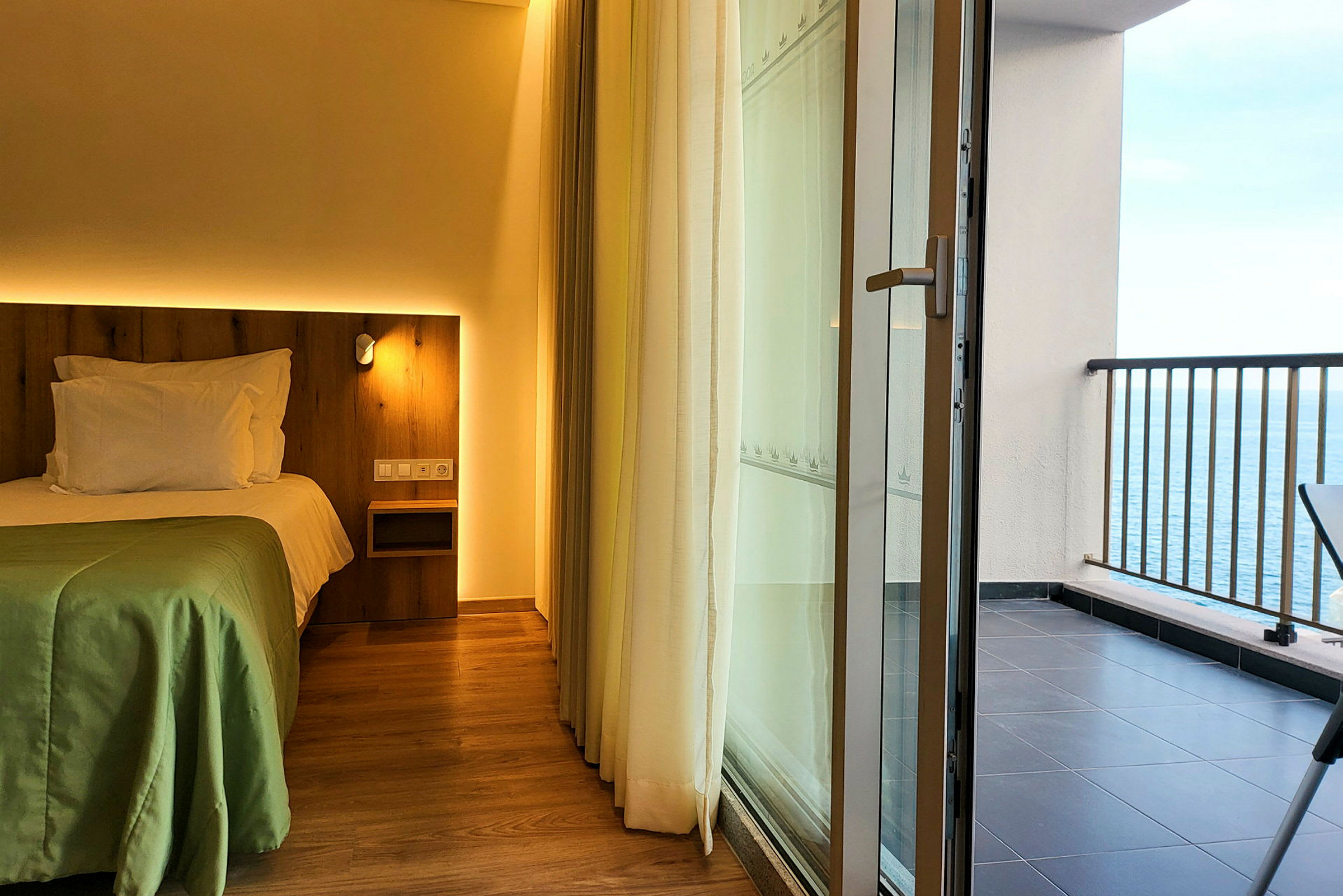 Hotellrum med säng och en balkong med utsikt över havet. (AI-genererad text)