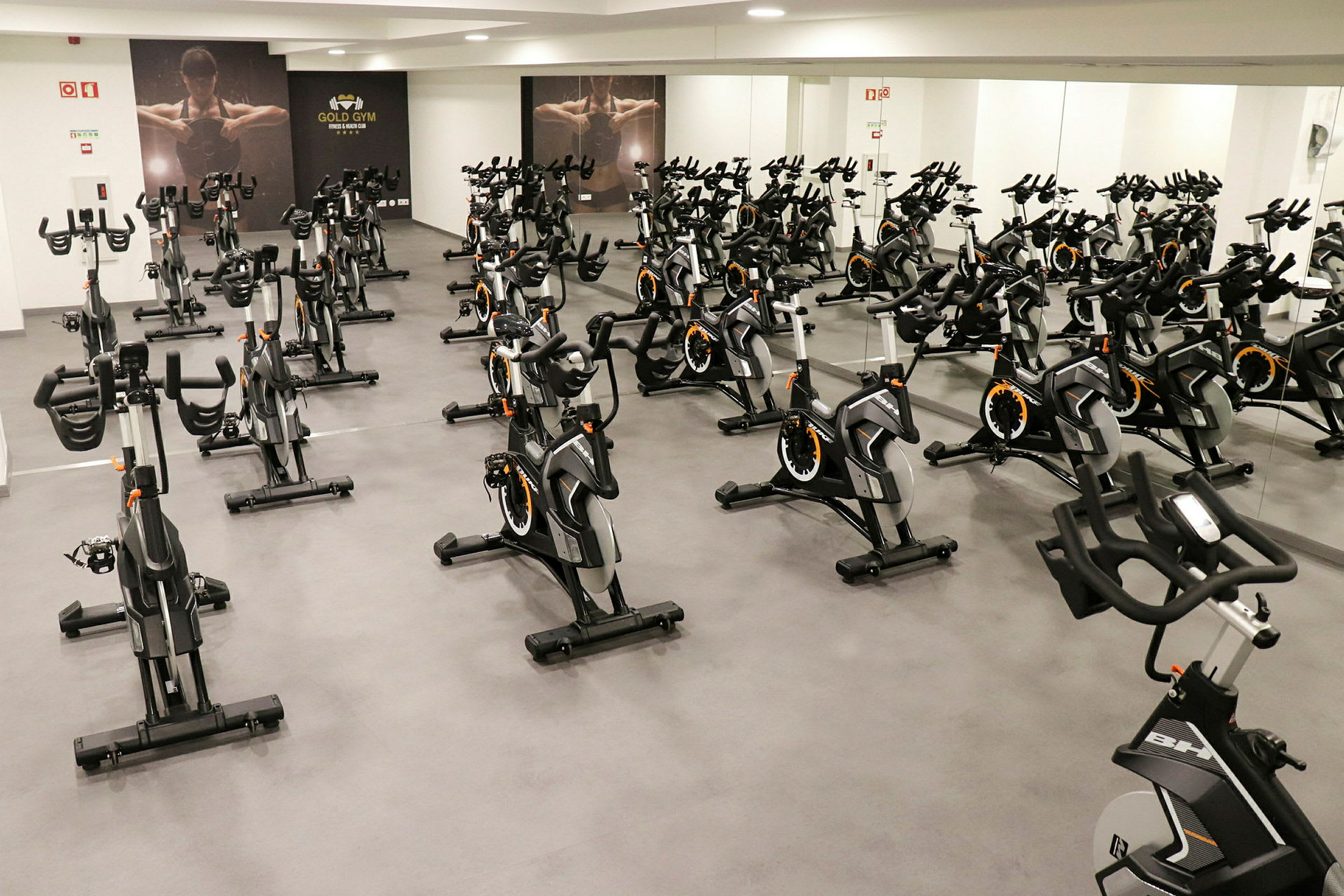 Ett gym med flera motionscyklar i ett rum med spegelväggar. (AI-genererad text)