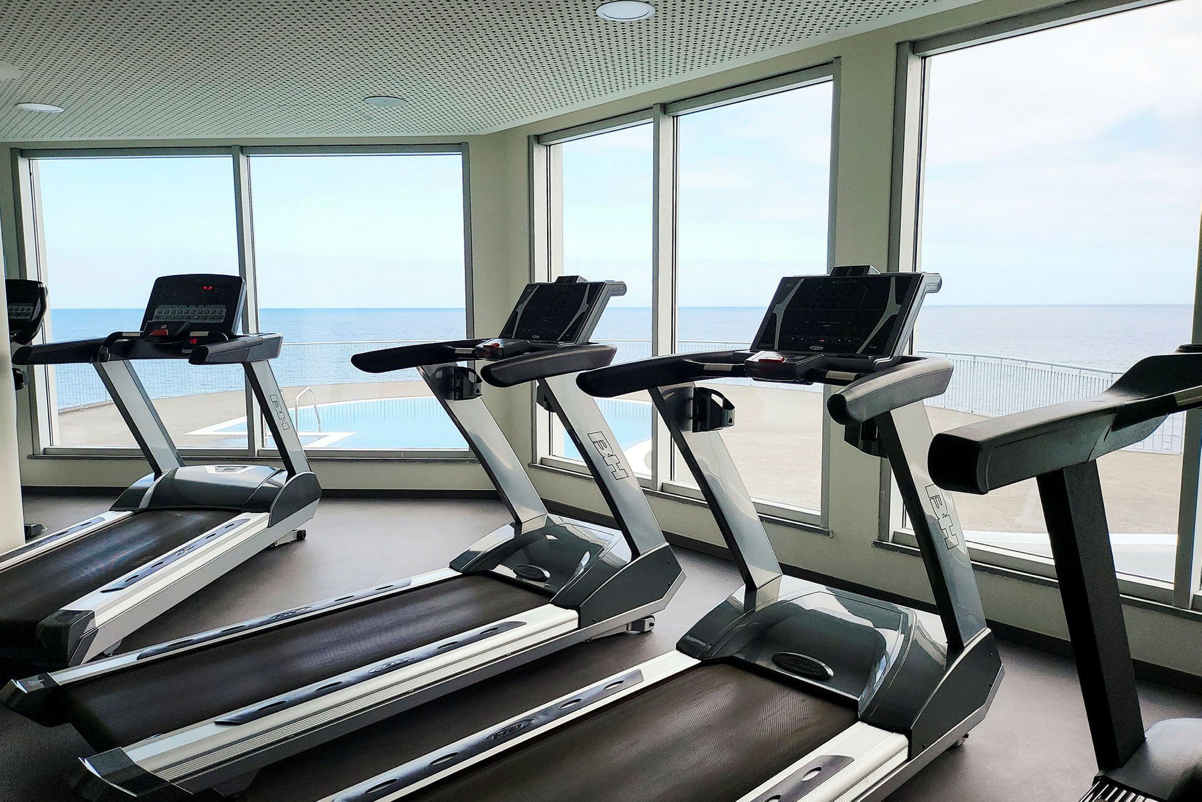 Löpband i ett gym med utsikt över havet. (AI-genererad text)