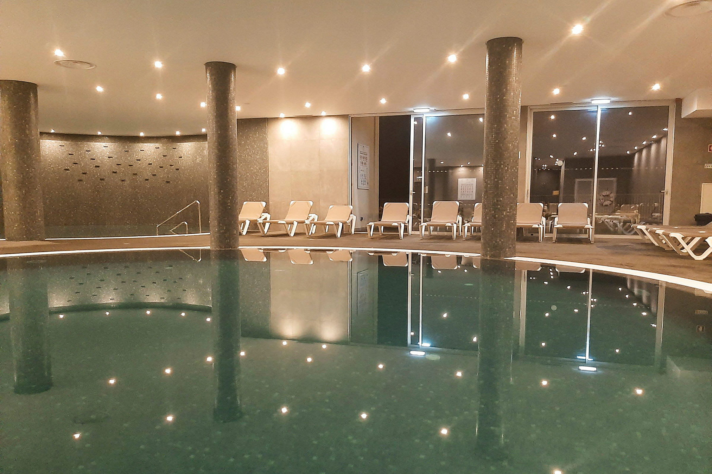 En inomhuspool med solstolar i bakgrunden. (AI-genererad text)