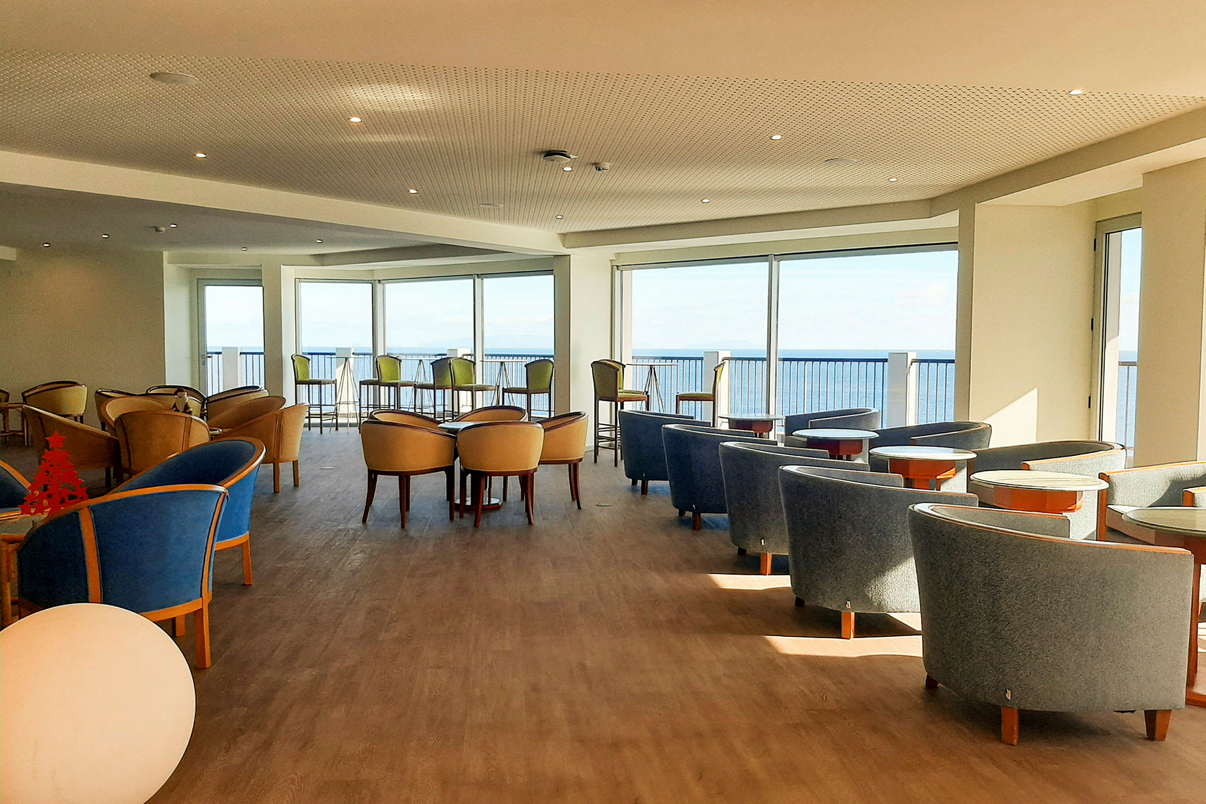 En interiörbild av en ljus sittgrupp med utsikt mot havet. (AI-genererad text)