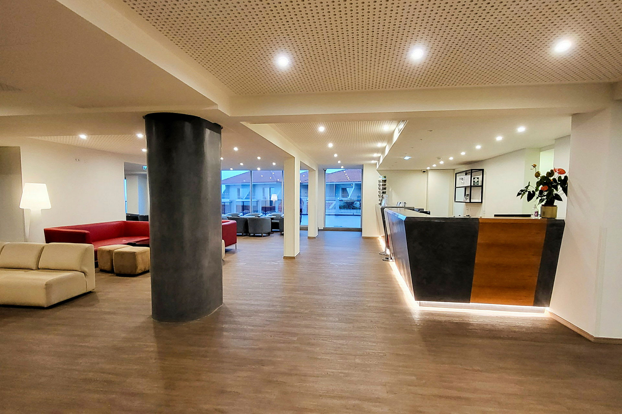 Hotellobby med sittgrupper, reception och stora fönster. (AI-genererad text)
