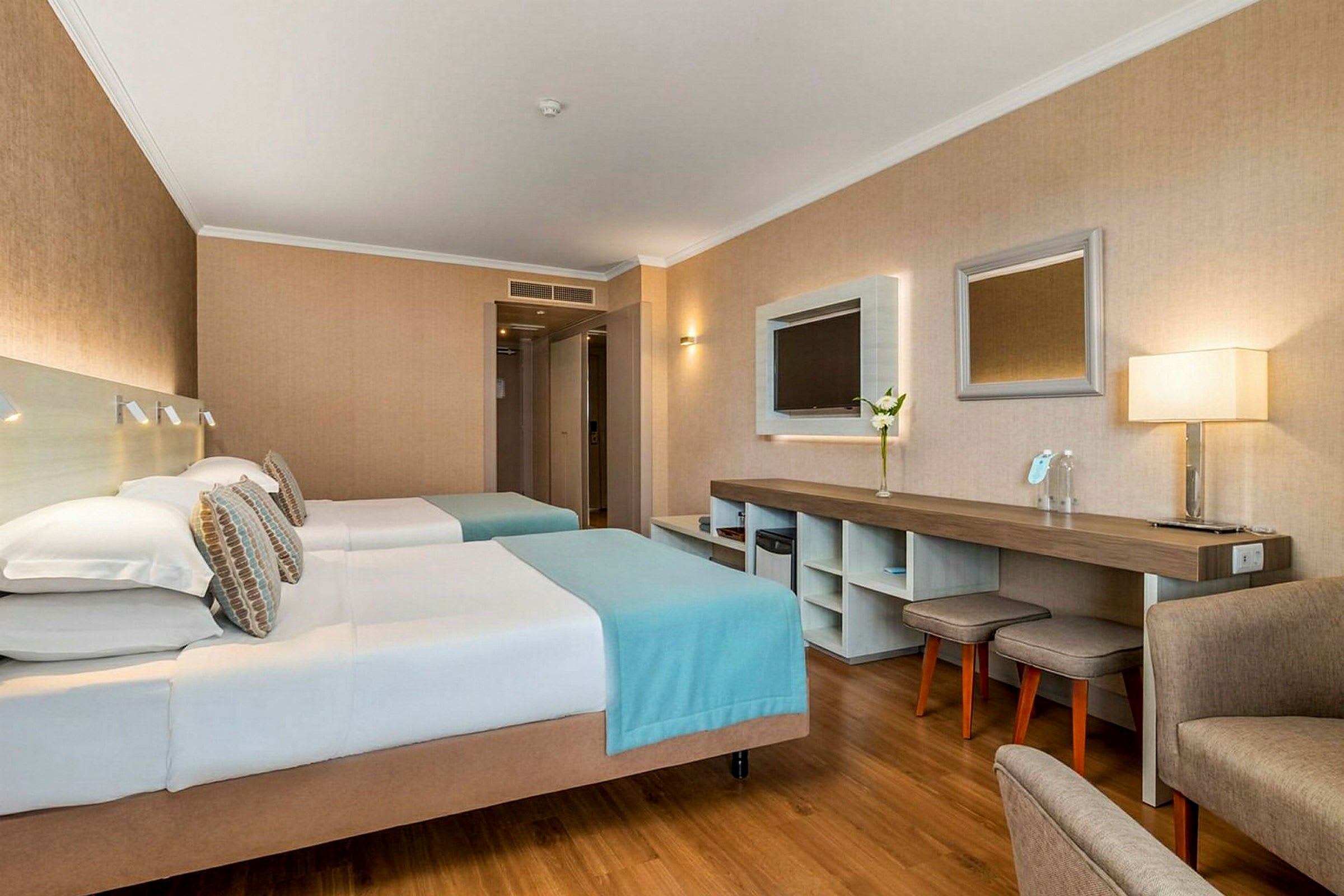 Hotellrum med två enkelsängar, arbetsyta och sittmöbler. (AI-genererad text)