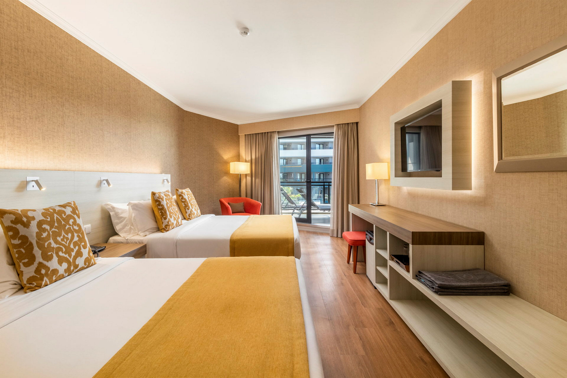 Hotellrum med två sängar, en fåtölj och utsikt mot balkong. (AI-genererad text)