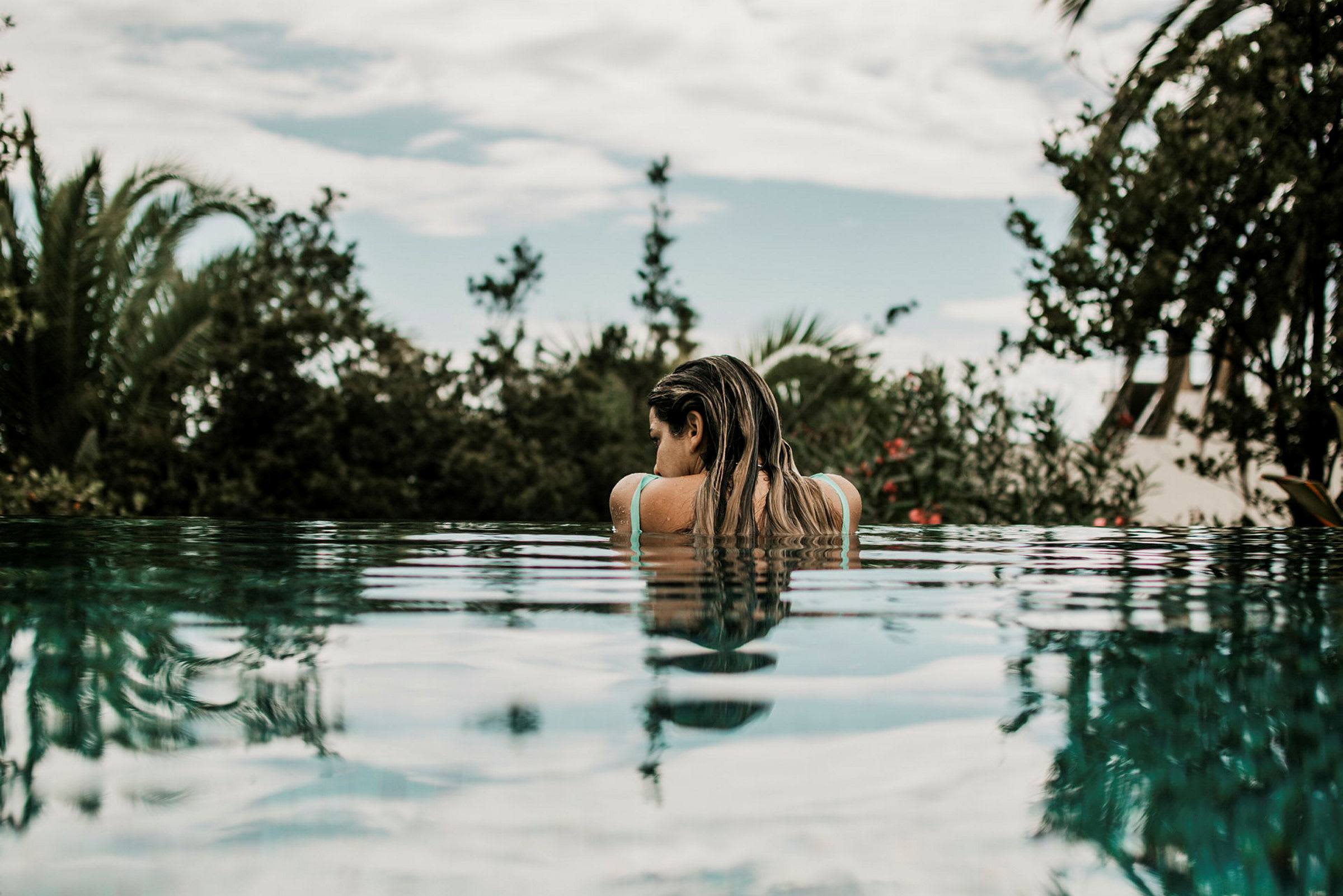 Person vid kanten av en pool med tropisk vegetation i bakgrunden. (AI-genererad text)