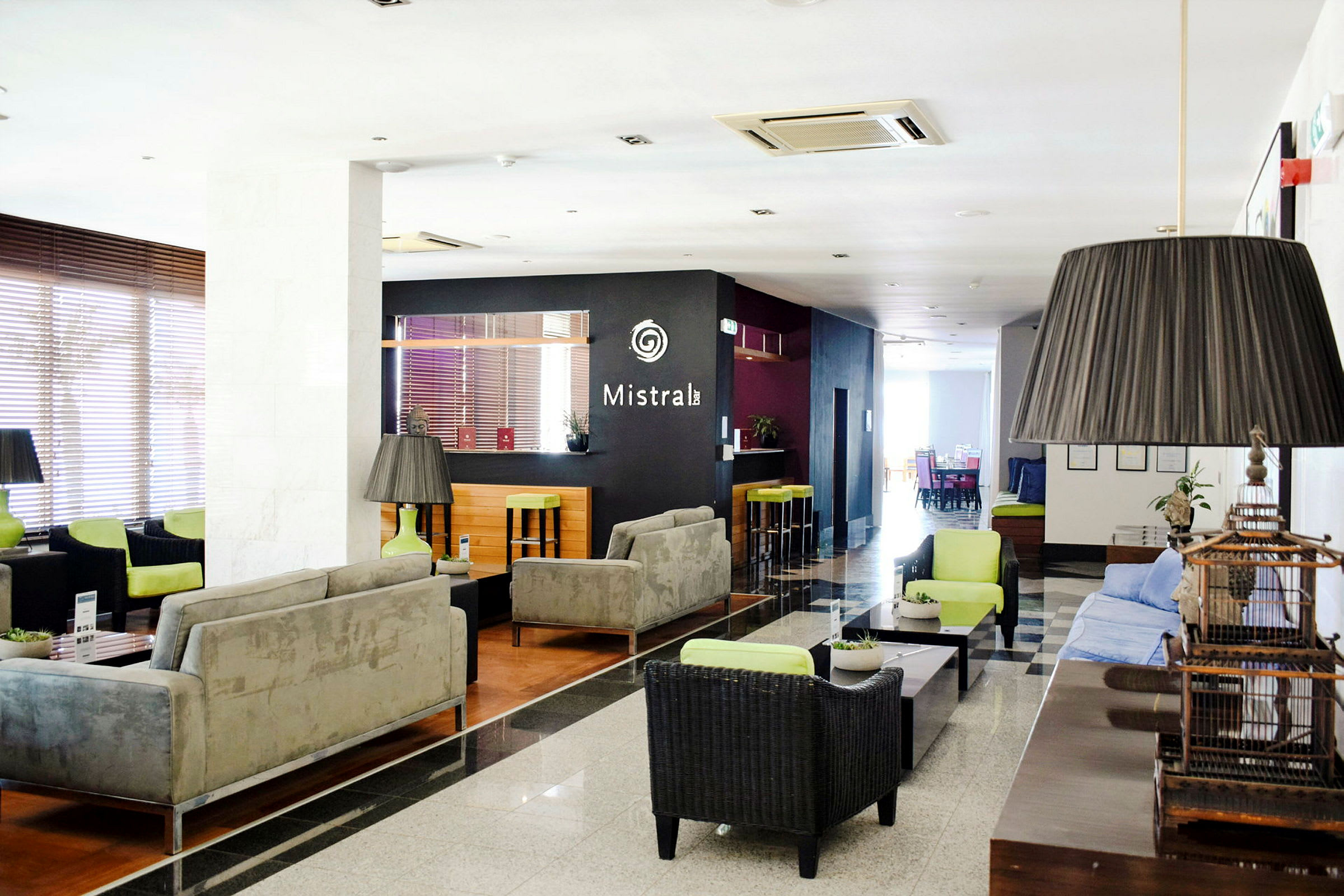 Ett hotelllobby med soffor, bord och en bar i bakgrunden. (AI-genererad text)