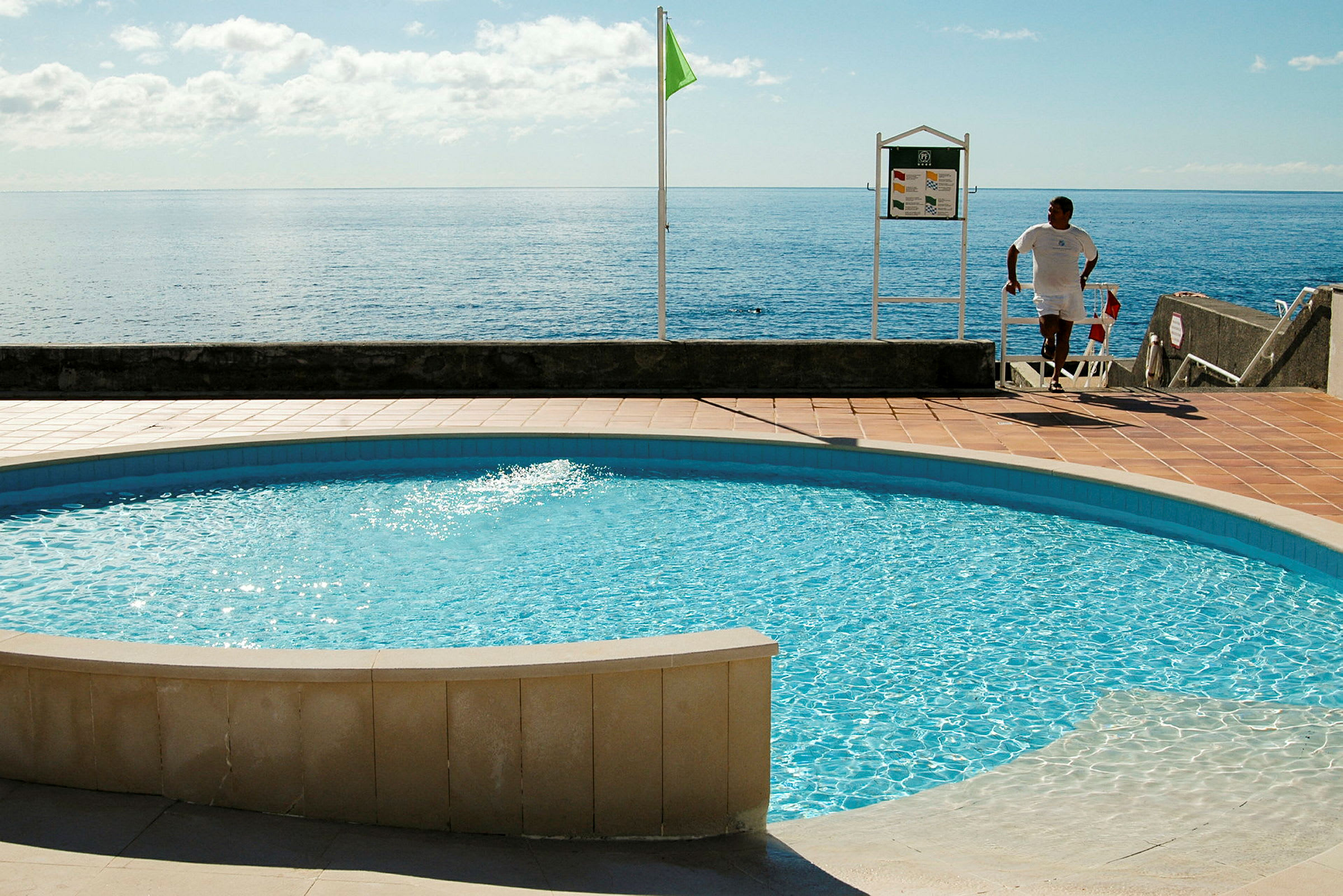 En utomhuspool nära havet med solsken. (AI-genererad text)