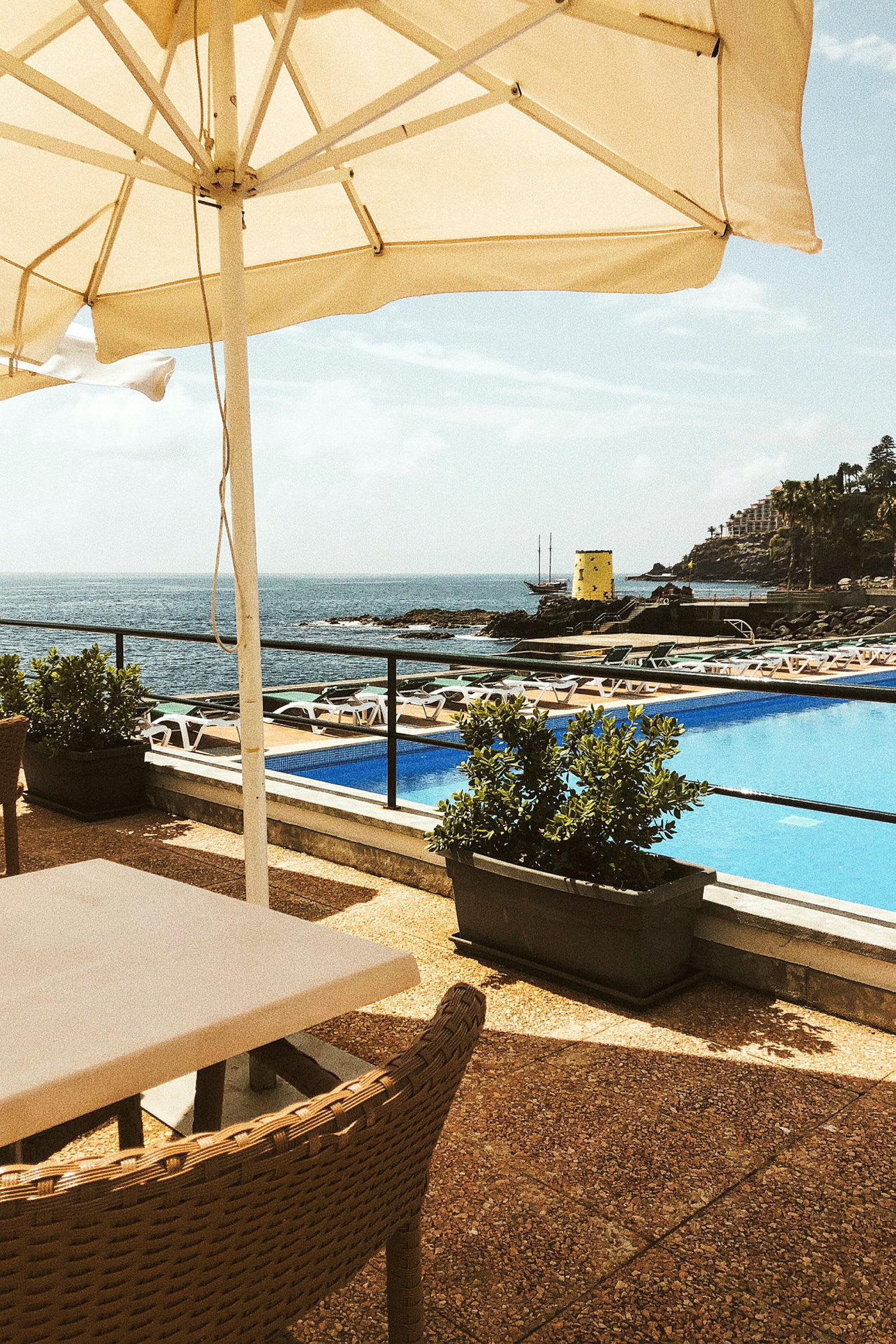 En solstol och ett parasoll vid en pool med utsikt över havet. (AI-genererad text)