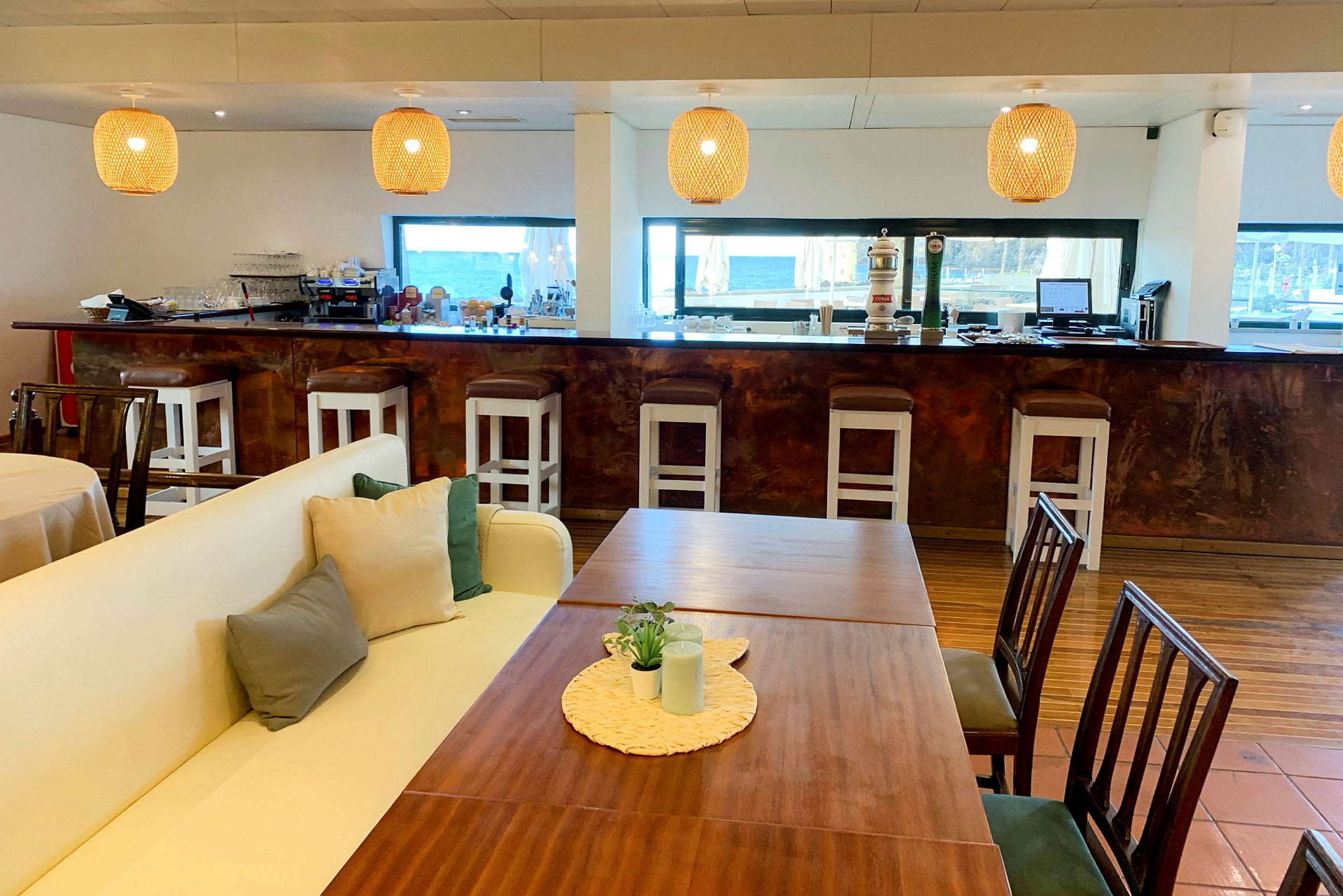 Ett caféområde med soffor, bord och stolar framför en bardisk med barstolar. (AI-genererad text)