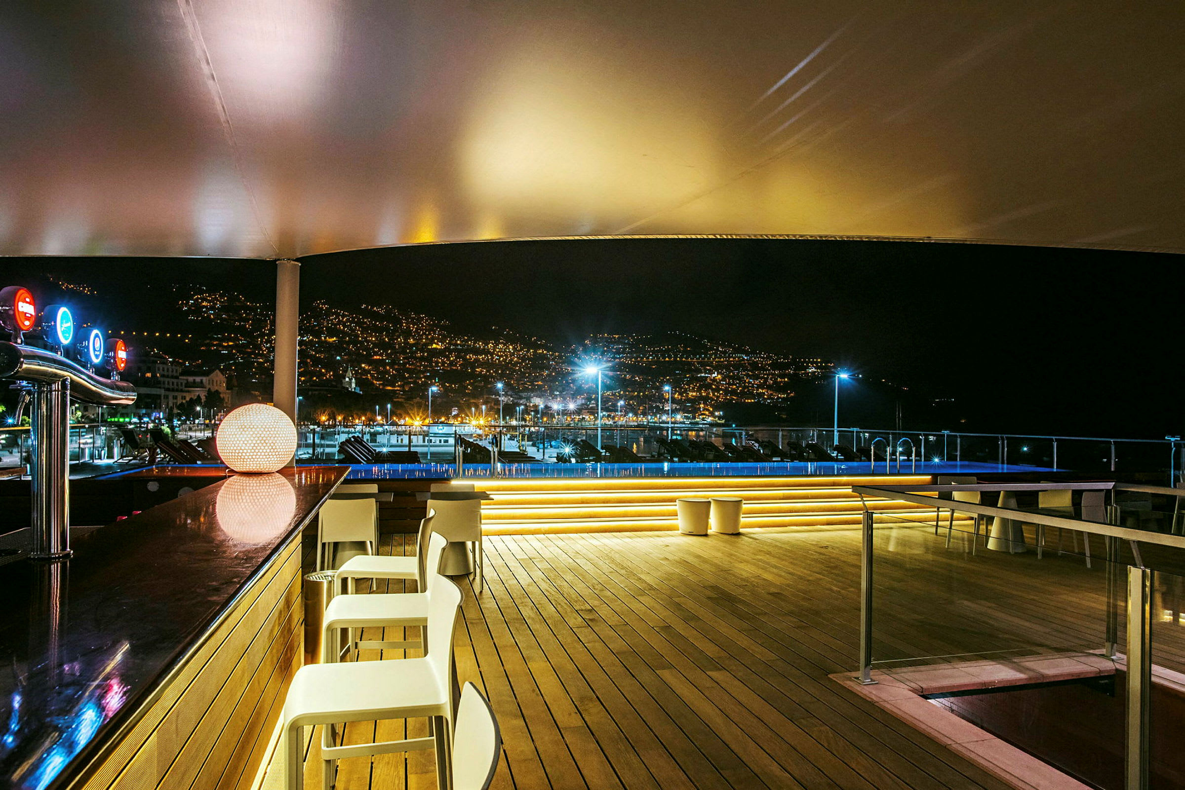 En belyst lounge med bar och utsikt över en stad vid natten. (AI-genererad text)