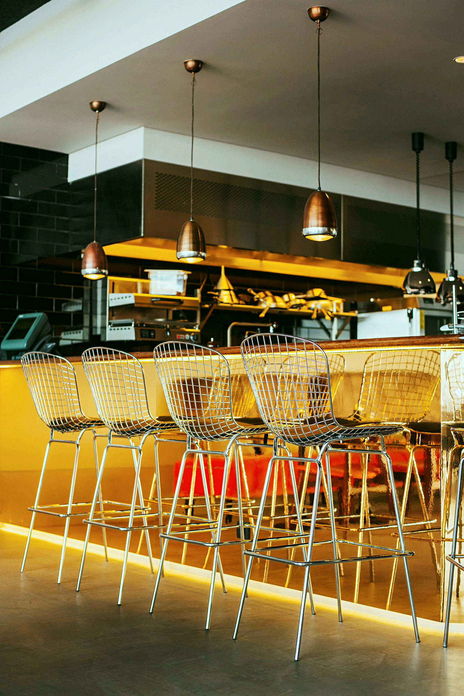 Barstolar vid en guldfärgad bardisk i en modern restaurangmiljö. (AI-genererad text)