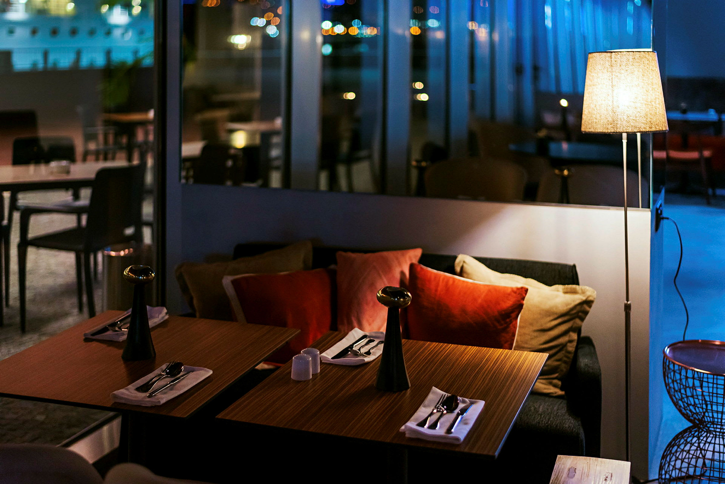 Två dukade bord med kuddar i en restaurang med lugn belysning. (AI-genererad text)