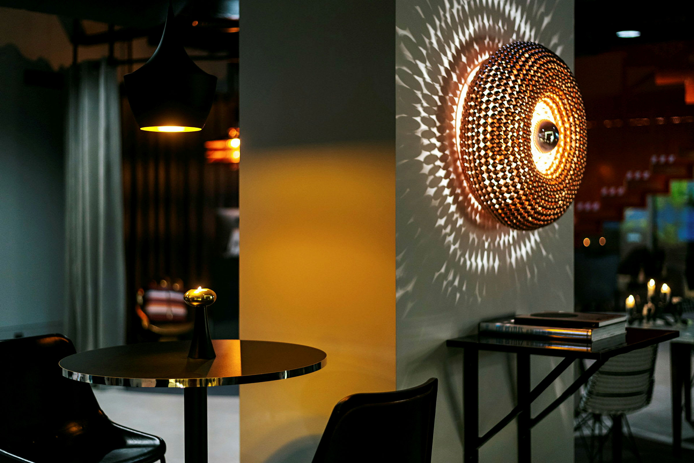En interiör med ett modernt bord med en liten lampa och en väggdekoration som sprider ljusmönster. (AI-genererad text)