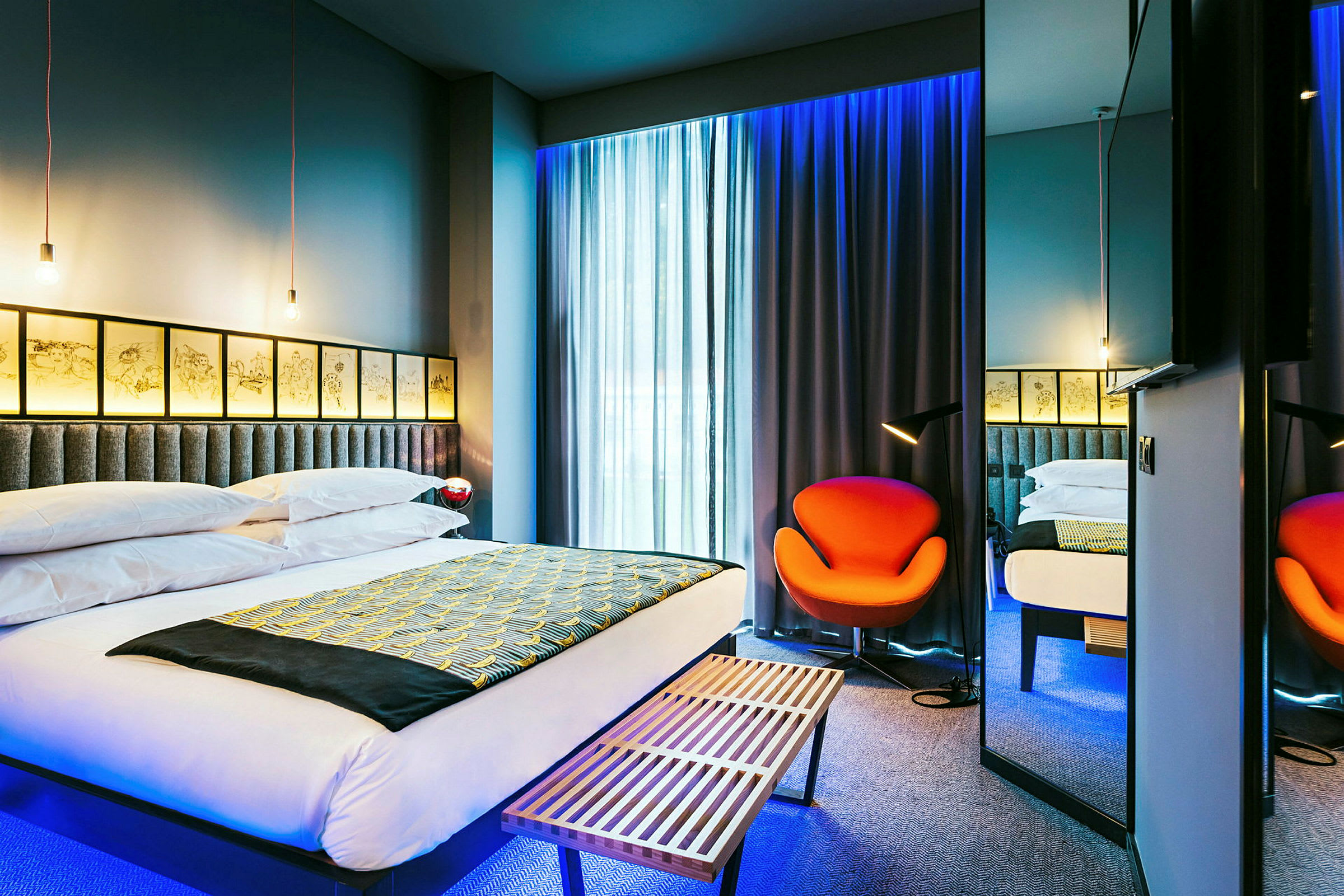 Ett modernt hotellrum med en stor säng, en orange stol och mjukt belysta gardiner. (AI-genererad text)