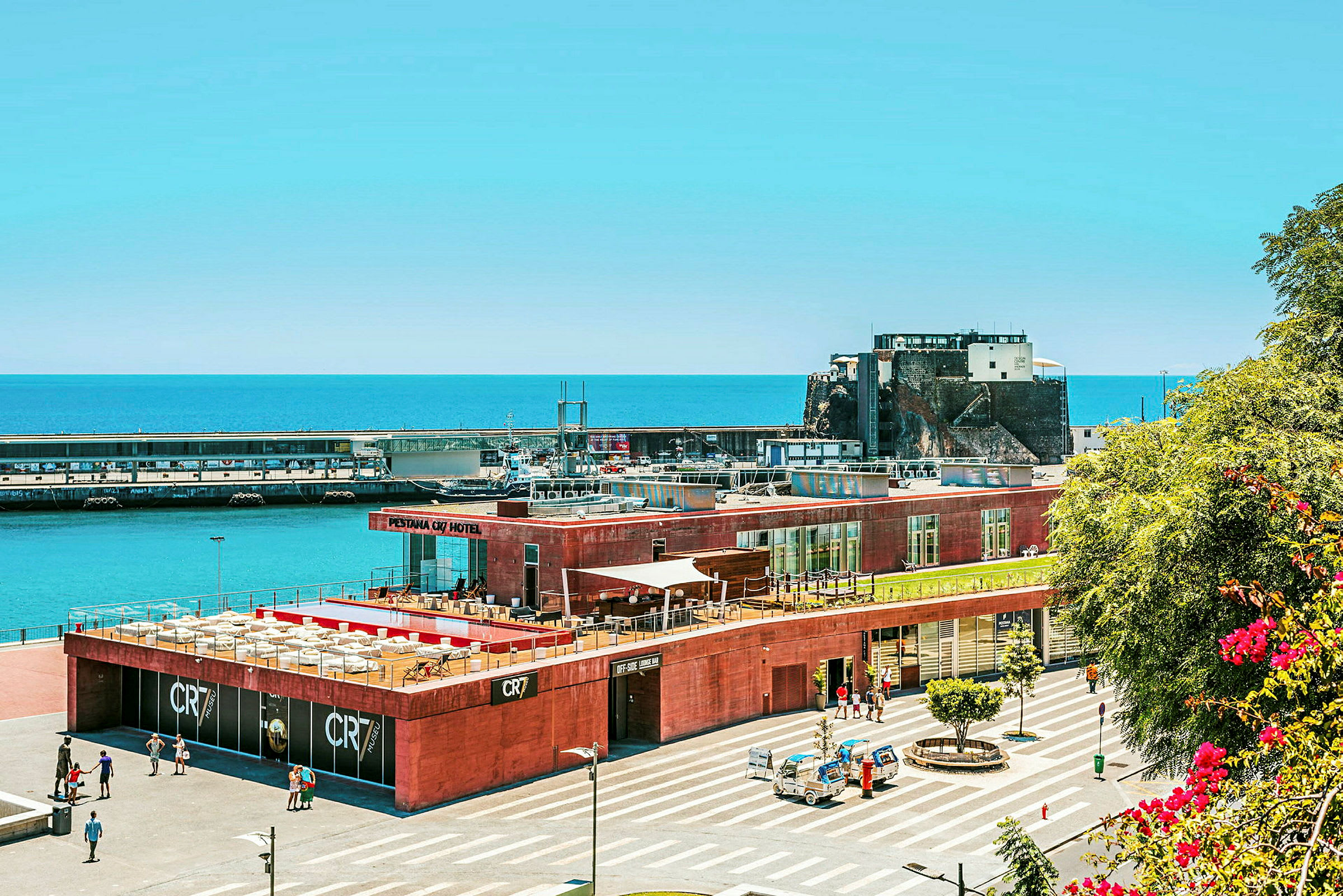 En hotellbyggnad nära havet med parkering och färjeterminal. (AI-genererad text)