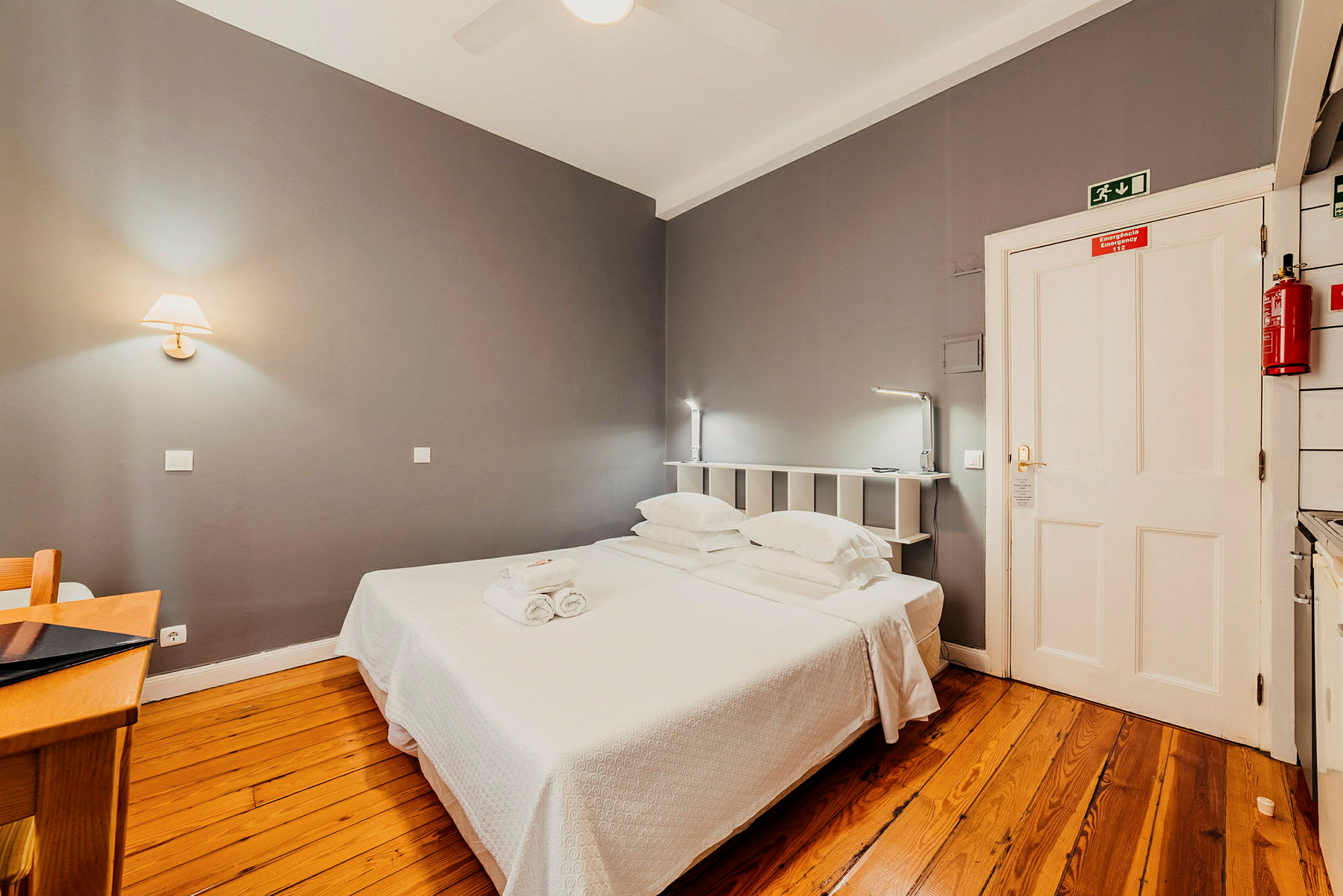Hotellrum med grå väggar, trägolv och en dubbelsäng. (AI-genererad text)