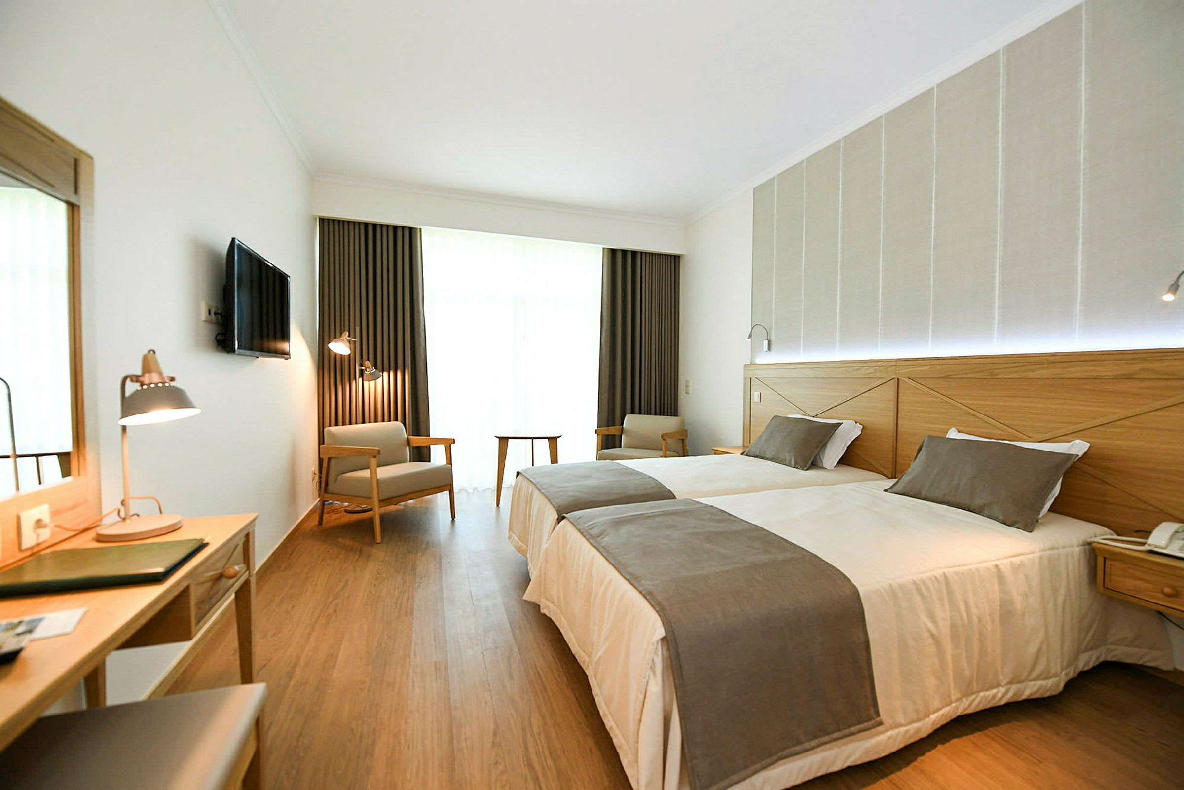 Hotelrum med två enkelsängar, skrivbord och sittplatser. (AI-genererad text)
