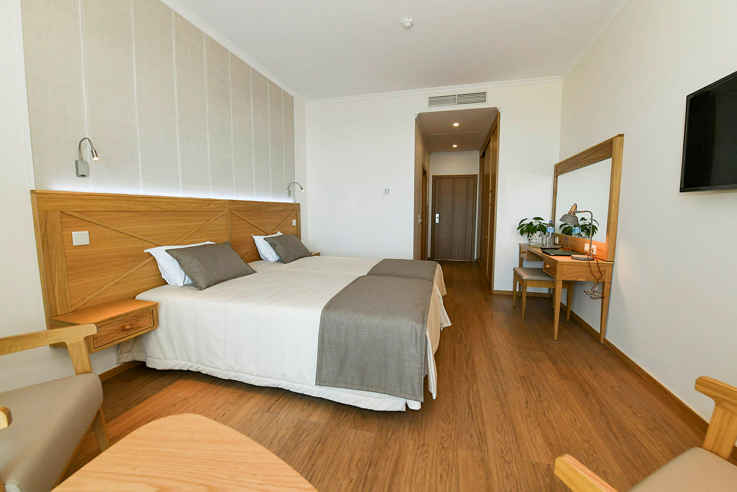 Modernt inrett hotellrum med två enkelsängar och möbler i trä. (AI-genererad text)