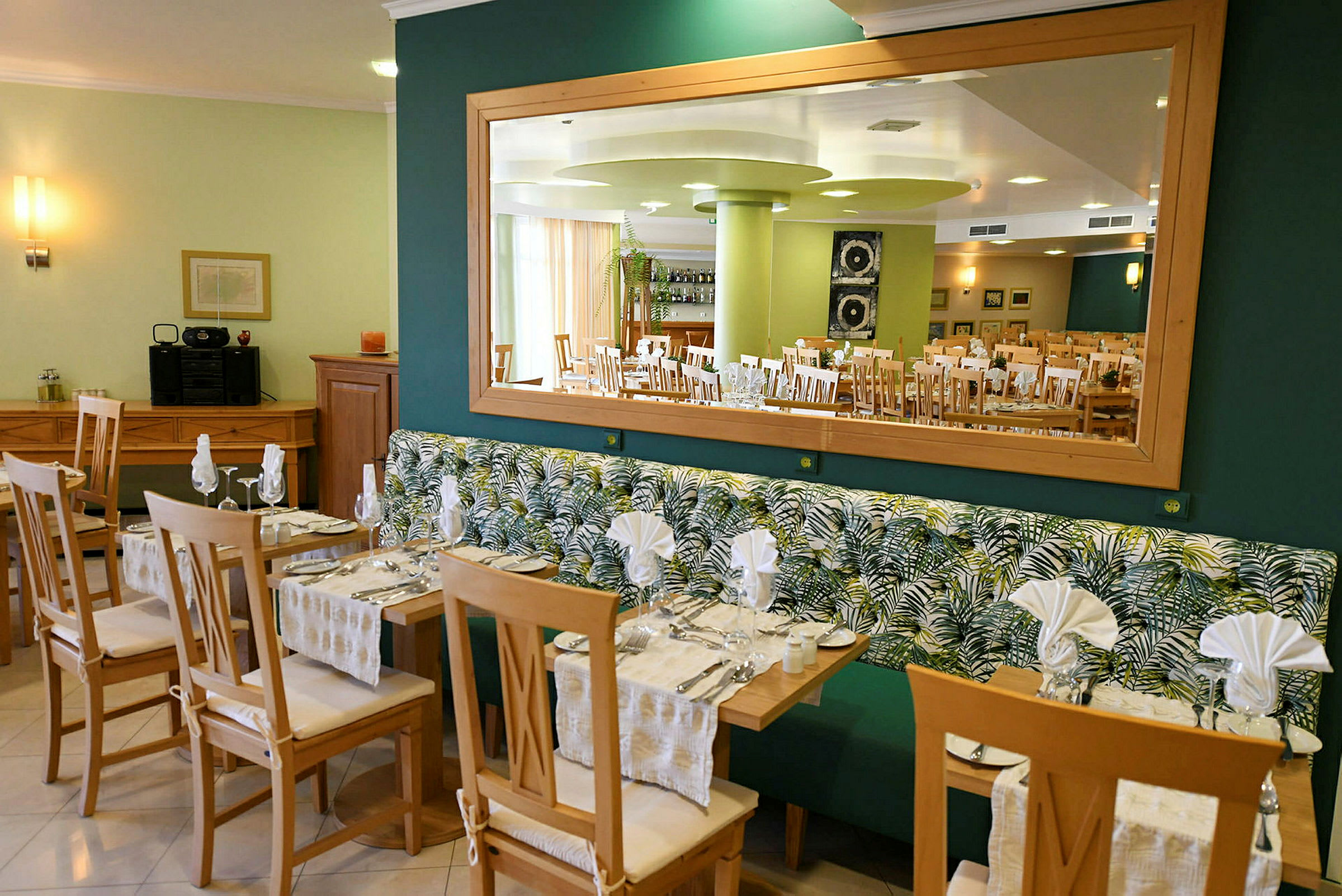 Restaurang med bord och stolar samt spegel på väggen. (AI-genererad text)
