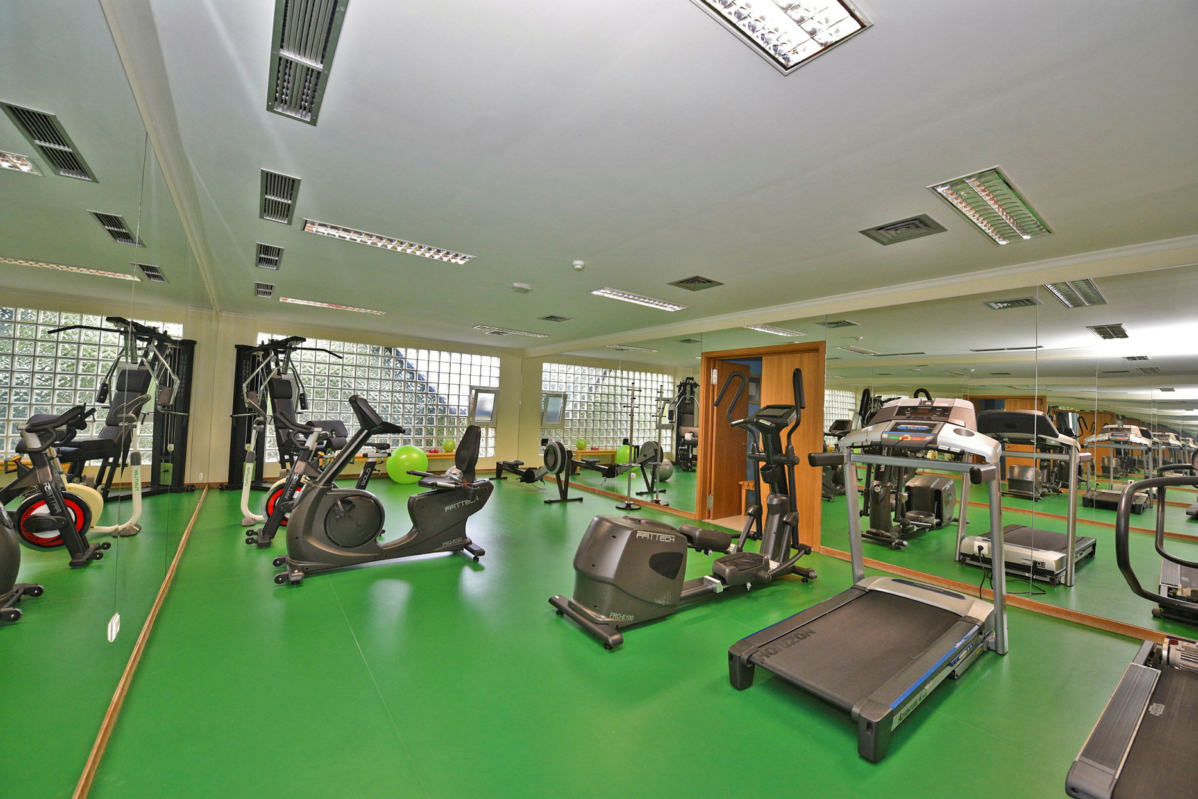 Ett gym med träningsmaskiner och grönt golv. (AI-genererad text)