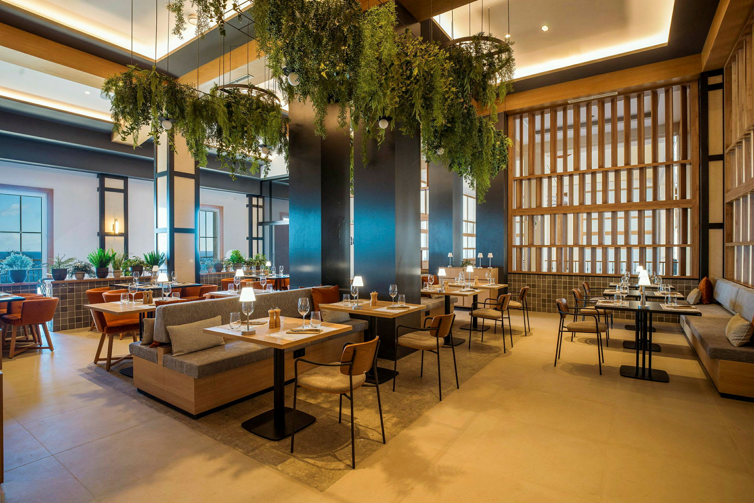 En modern restaurang med trämöbler, gröna växtdekorationer och stoftat ljus. (AI-genererad text)