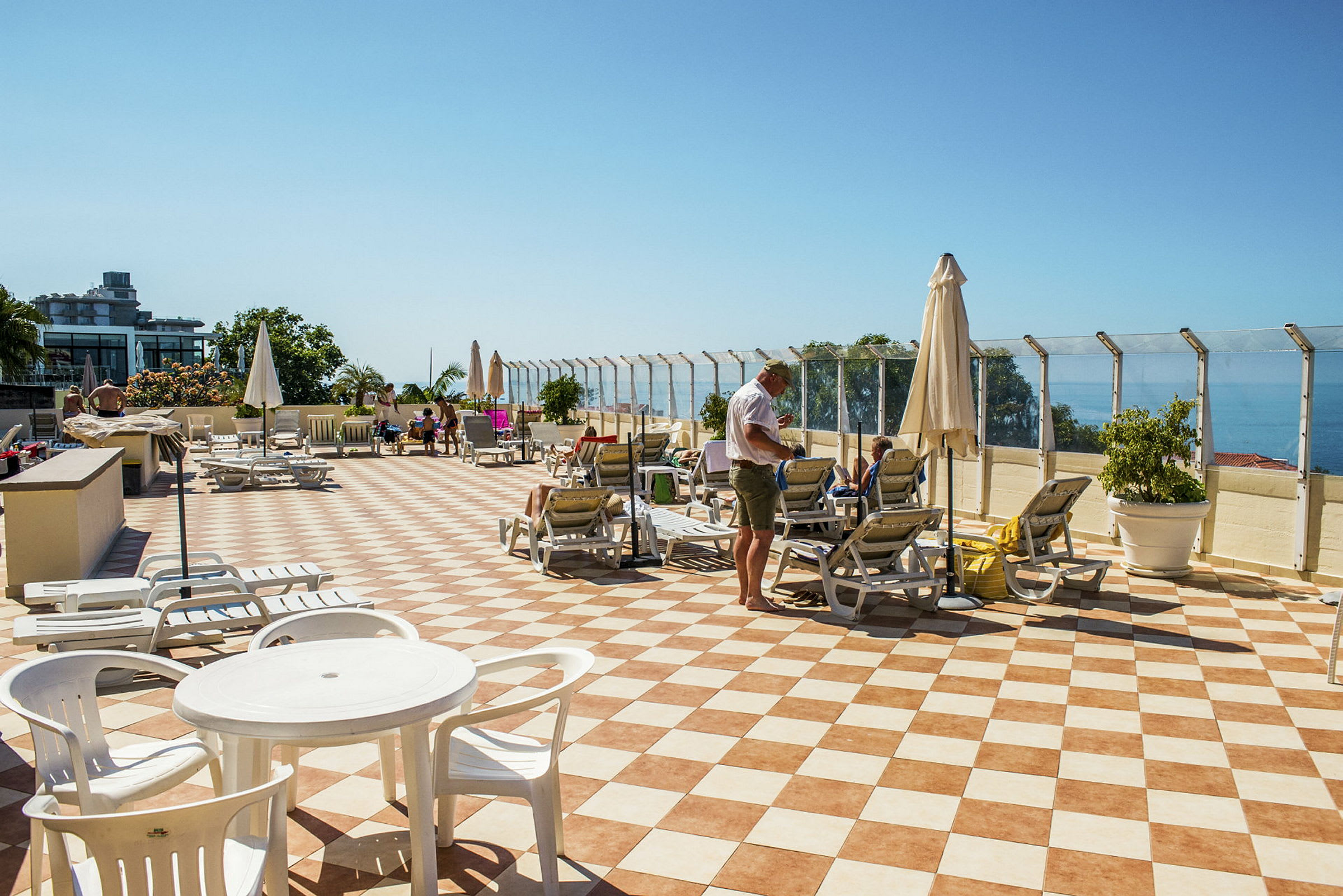 En solterrass med solstolar och parasoller samt havsutsikt. (AI-genererad text)