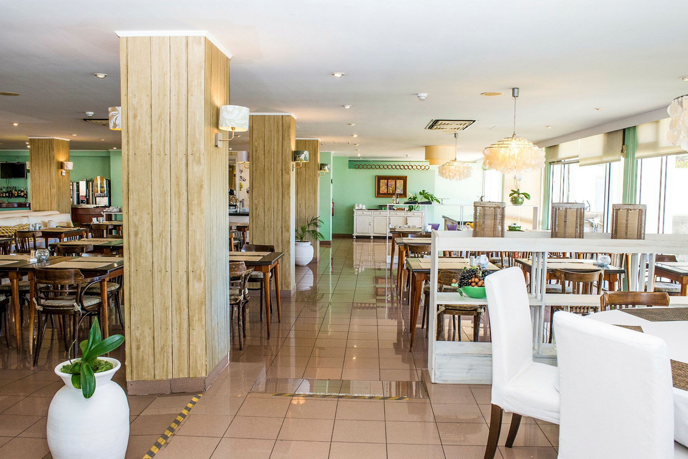 En restaurang med bord och stolar utplacerade i ljusa omgivningar. (AI-genererad text)