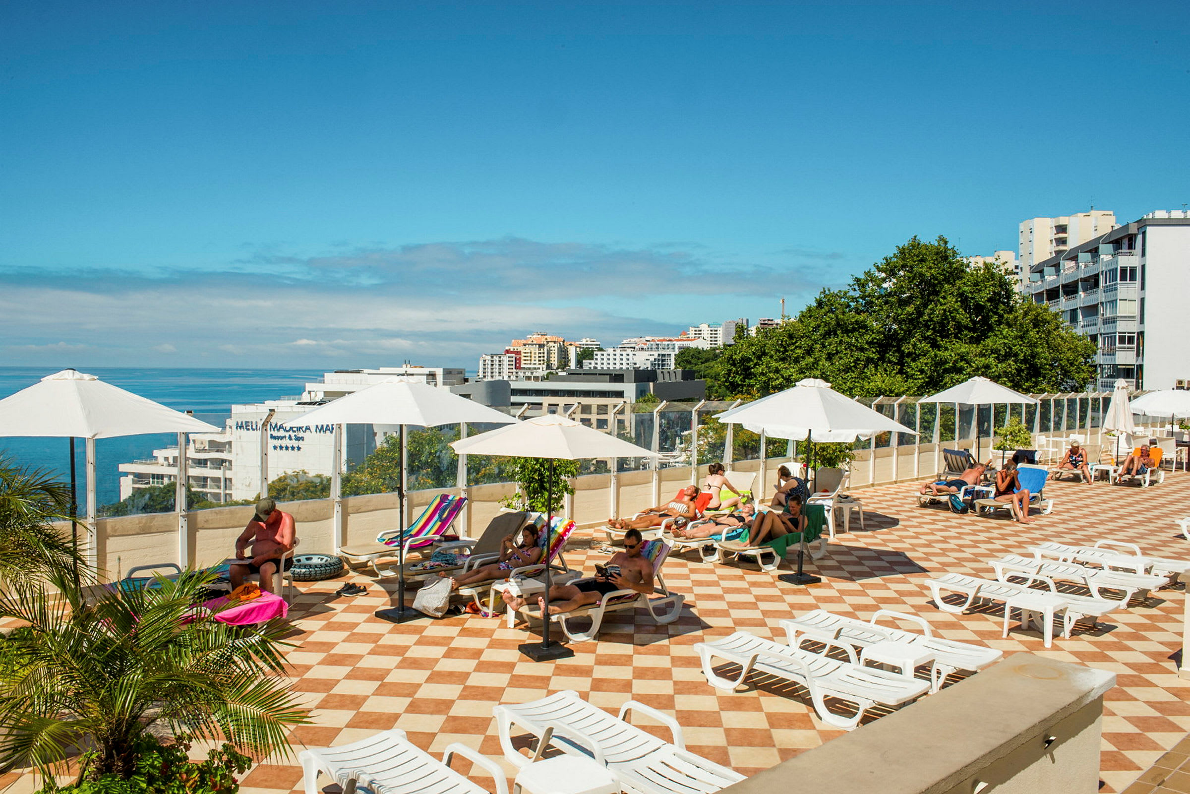 Solterrass med solstolar och parasoller, med utsikt över havet. (AI-genererad text)