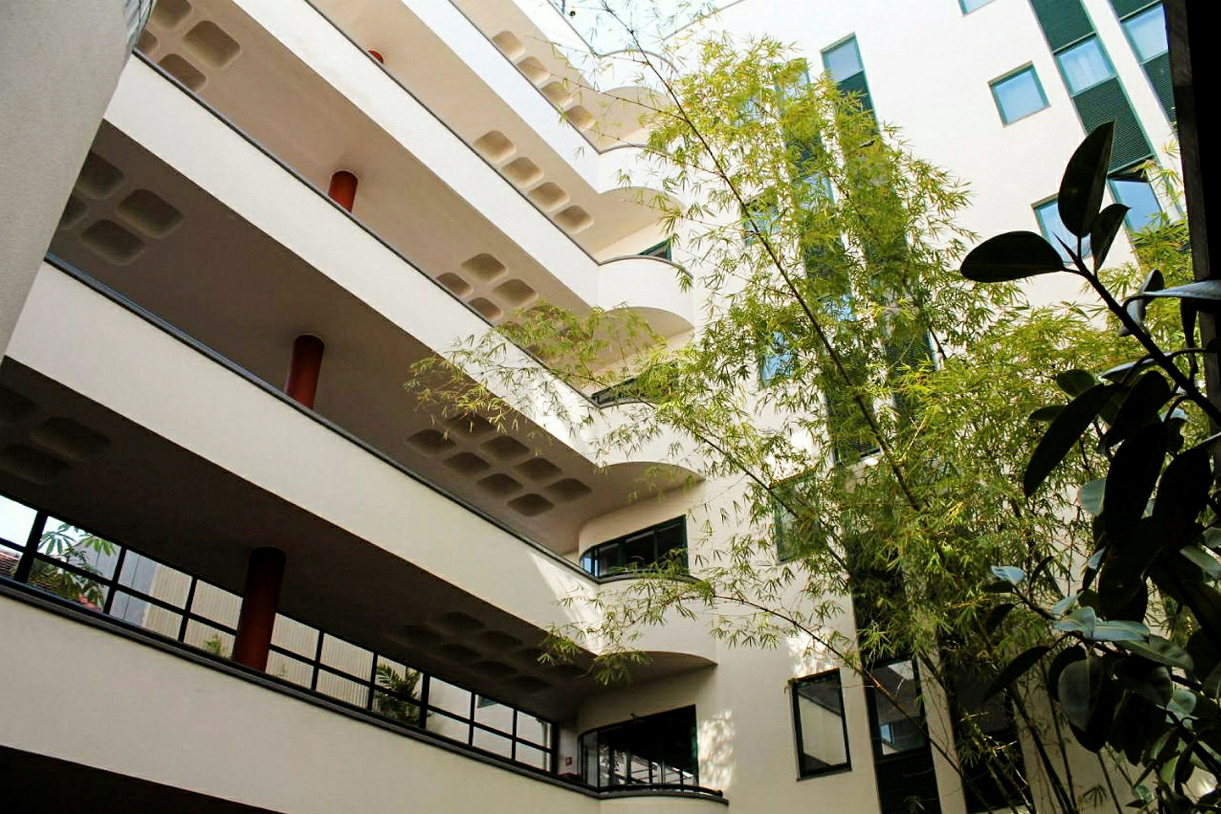 Flerfamiljshus med flera våningsplan och en innergård med gröna växter. (AI-genererad text)