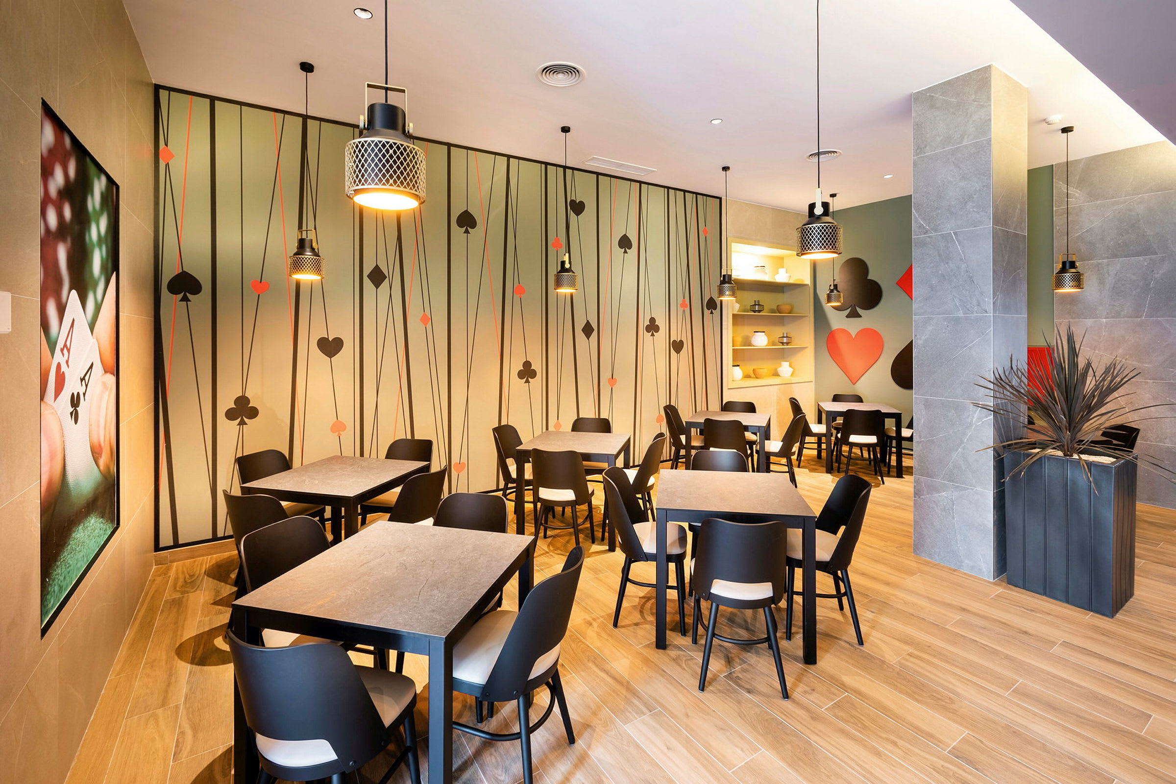 Bild av en restaurangmiljö med spelkortstema, sittgrupper och väggdekorationer. (AI-genererad text)