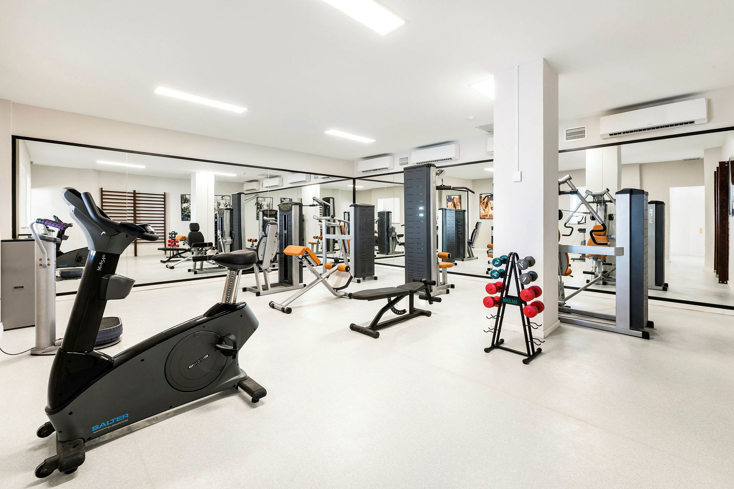 Gym med träningsutrustning och speglar på väggarna. (AI-genererad text)
