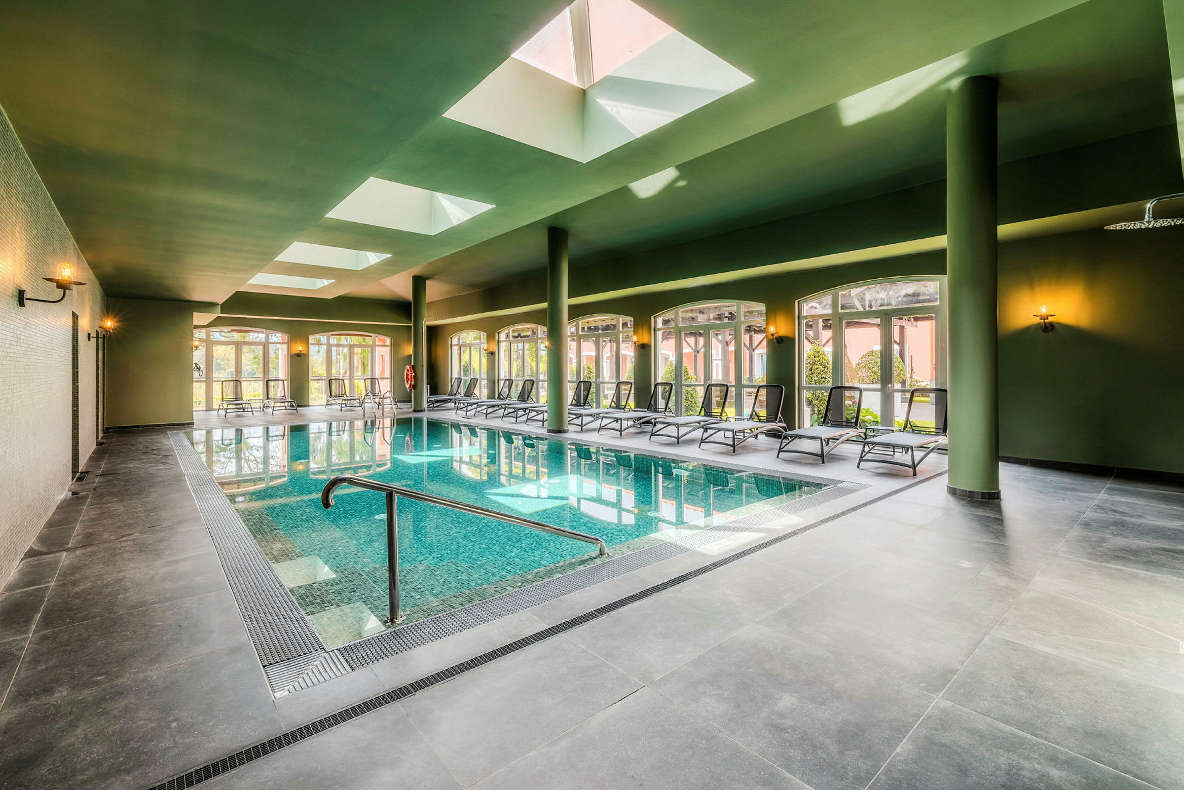 Inomhuspool med solstolar och takfönster. (AI-genererad text)