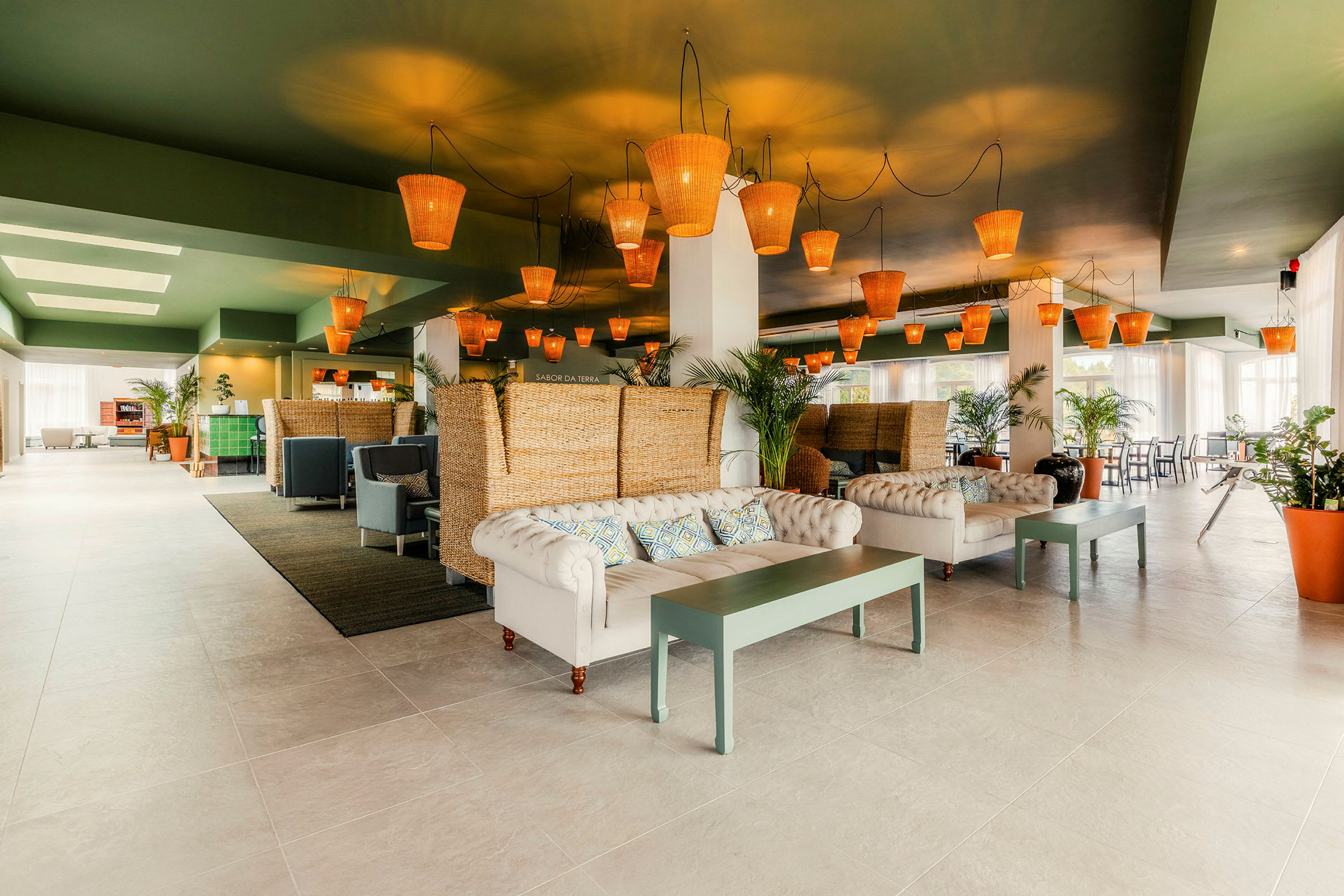 En modern och elegant lobby med soffor, bord och rottinglampor i taket. (AI-genererad text)
