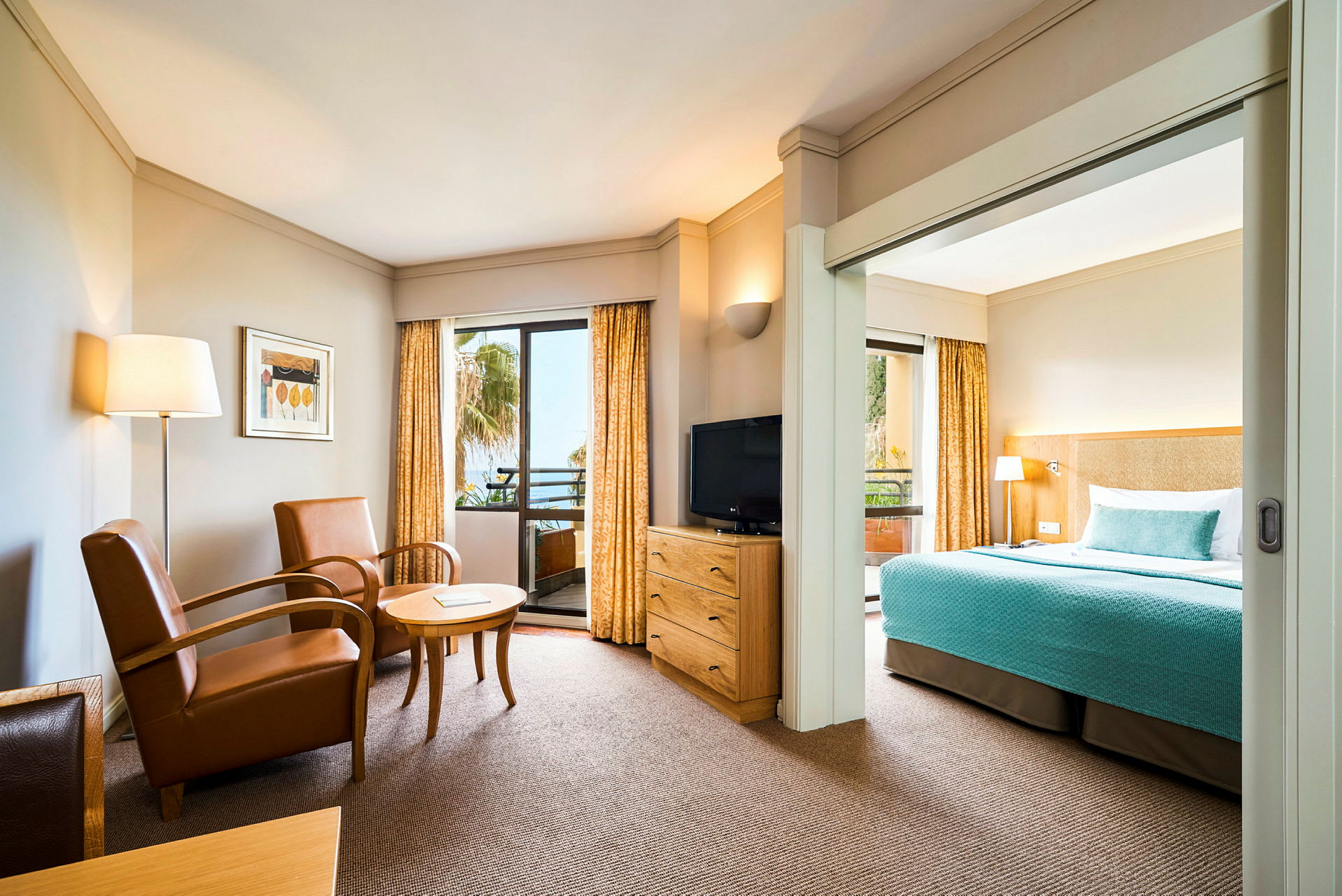 Ett hotellrum med sittgrupp, TV och säng med blå överkast. (AI-genererad text)