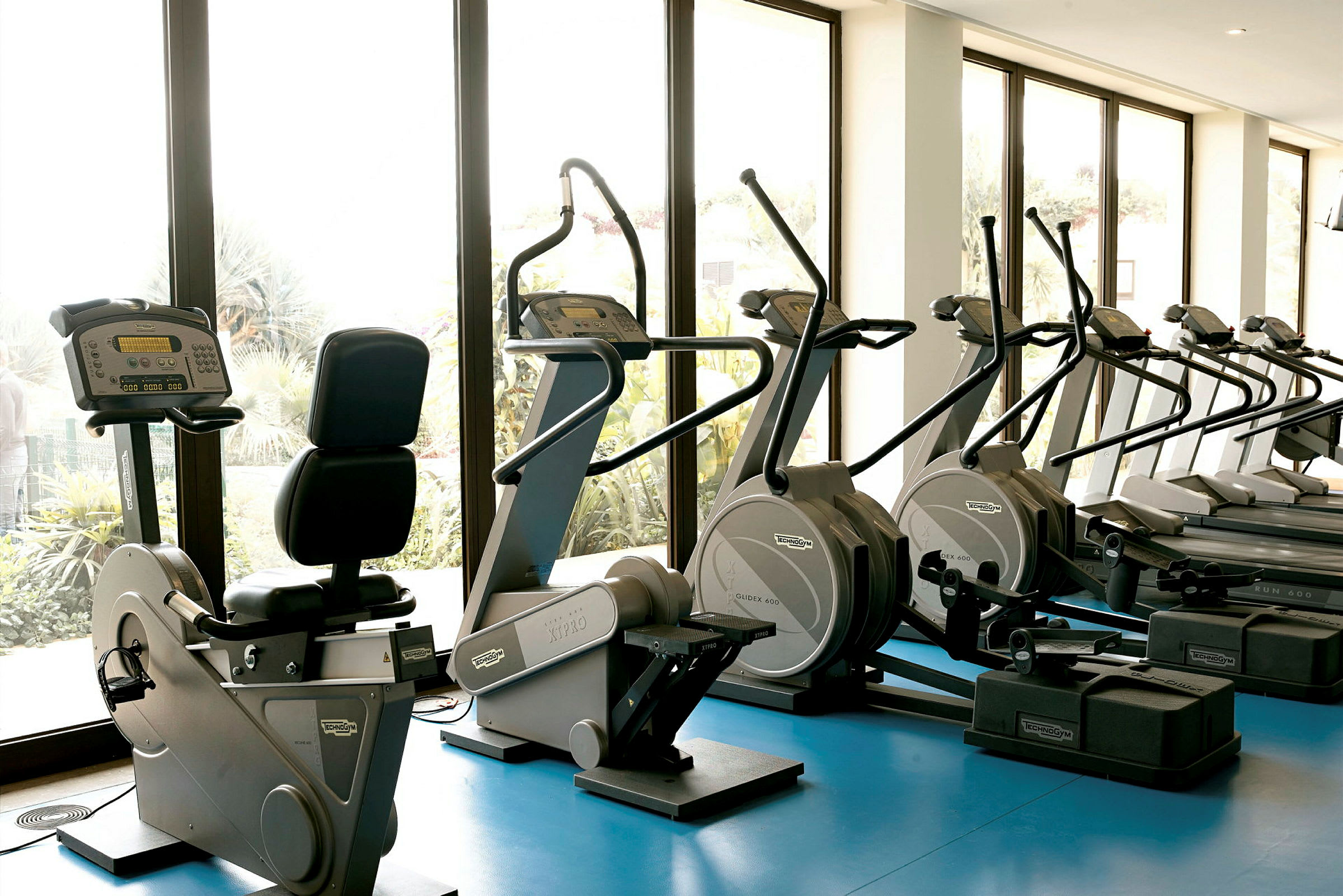 Ett gym med träningsmaskiner framför stora fönster. (AI-genererad text)